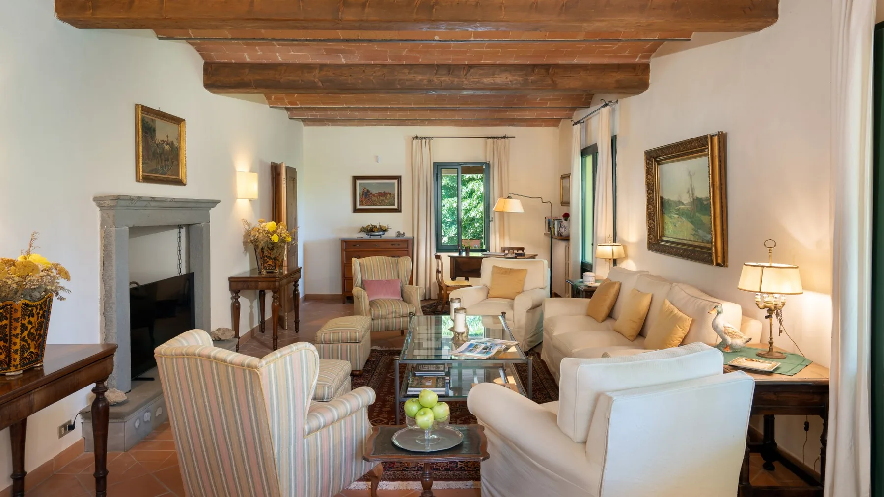 Una sala de estar con asientos claros, una mesa de centro de vidrio y vigas de madera expuestas.