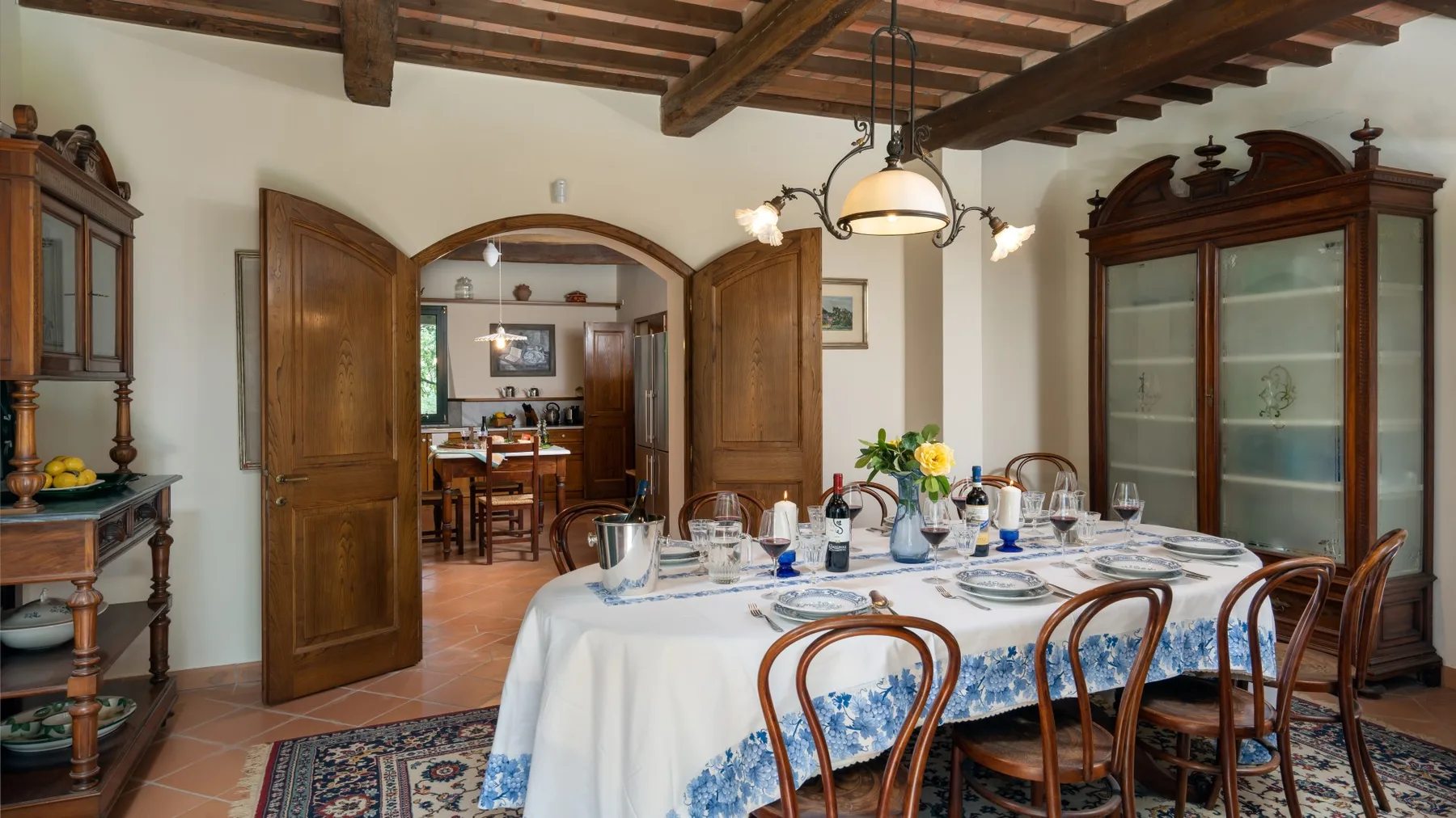 Un comedor con una mesa larga preparada para comer bajo vigas de madera expuestas.