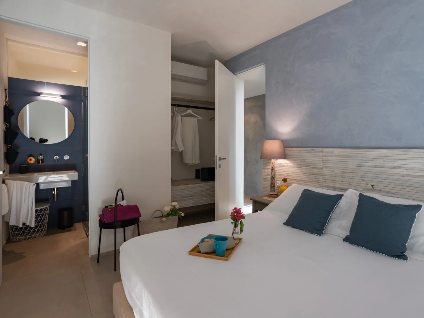 Un dormitorio con una cama bien hecha y un armario abierto.