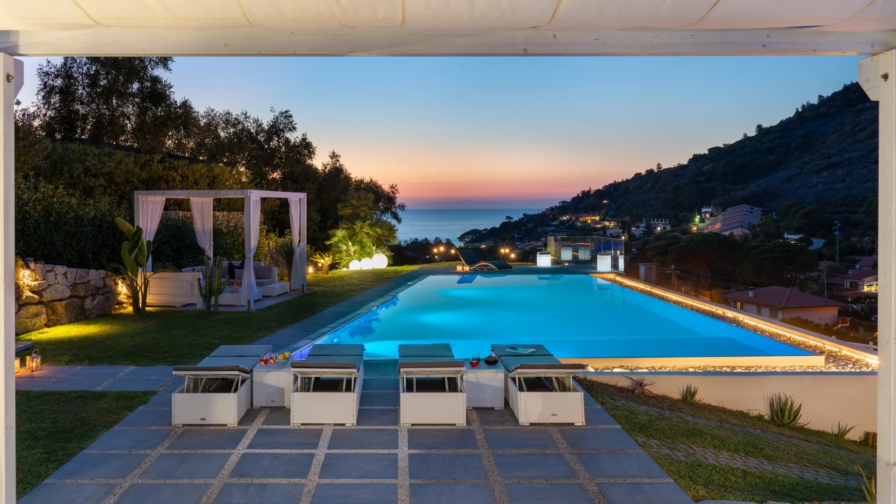 Una piscina al aire libre ofrece vistas a una colina costera al atardecer.