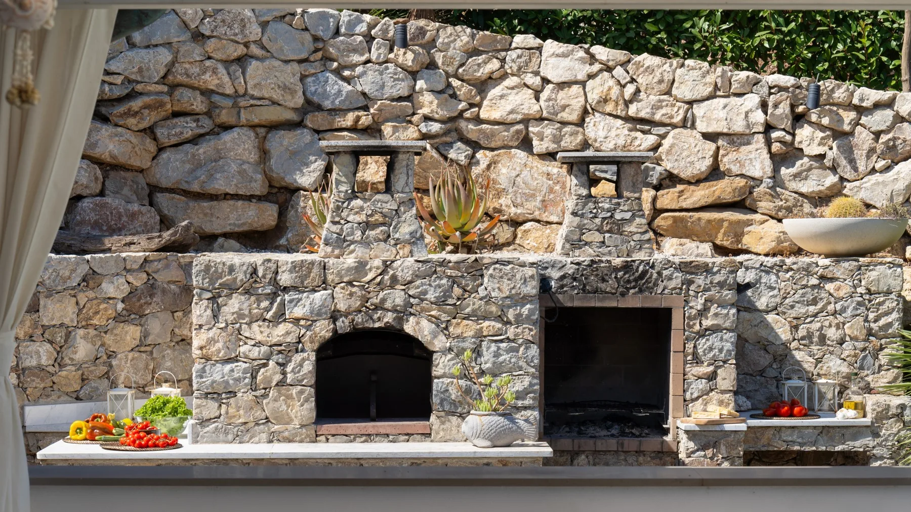 Una zona de cocina exterior de piedra con parrilla y encimera.