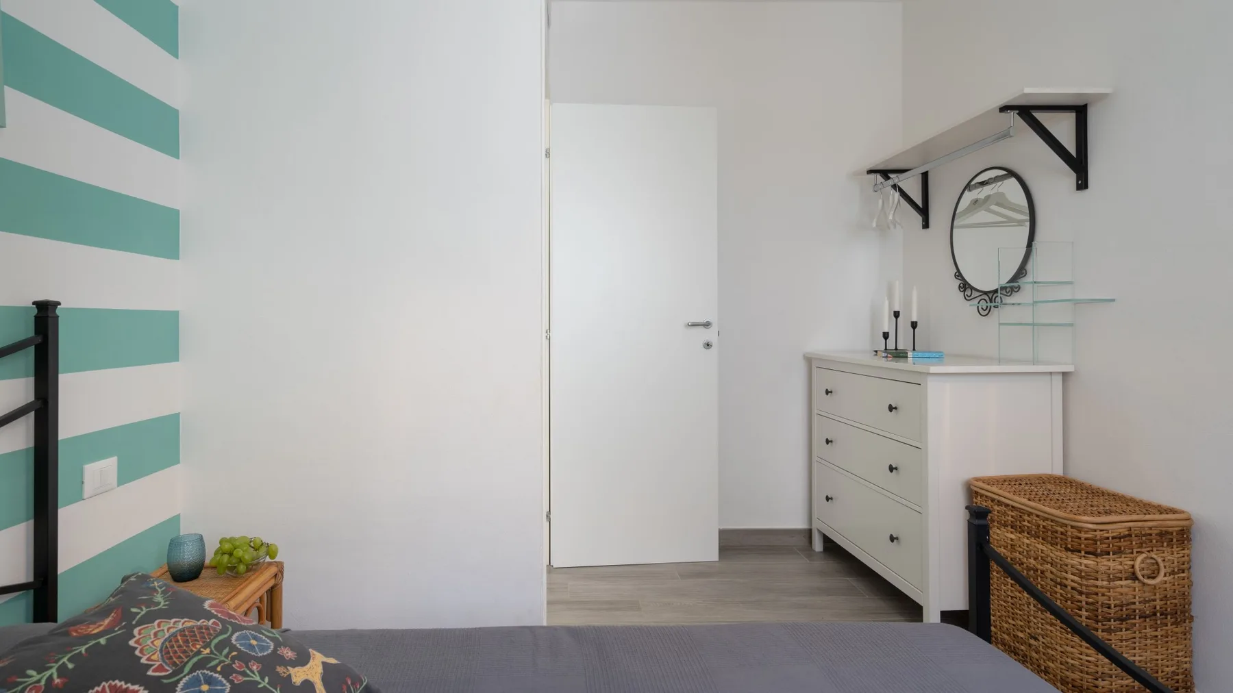 Un dormitorio con una cama, una cómoda blanca y una cesta tejida.