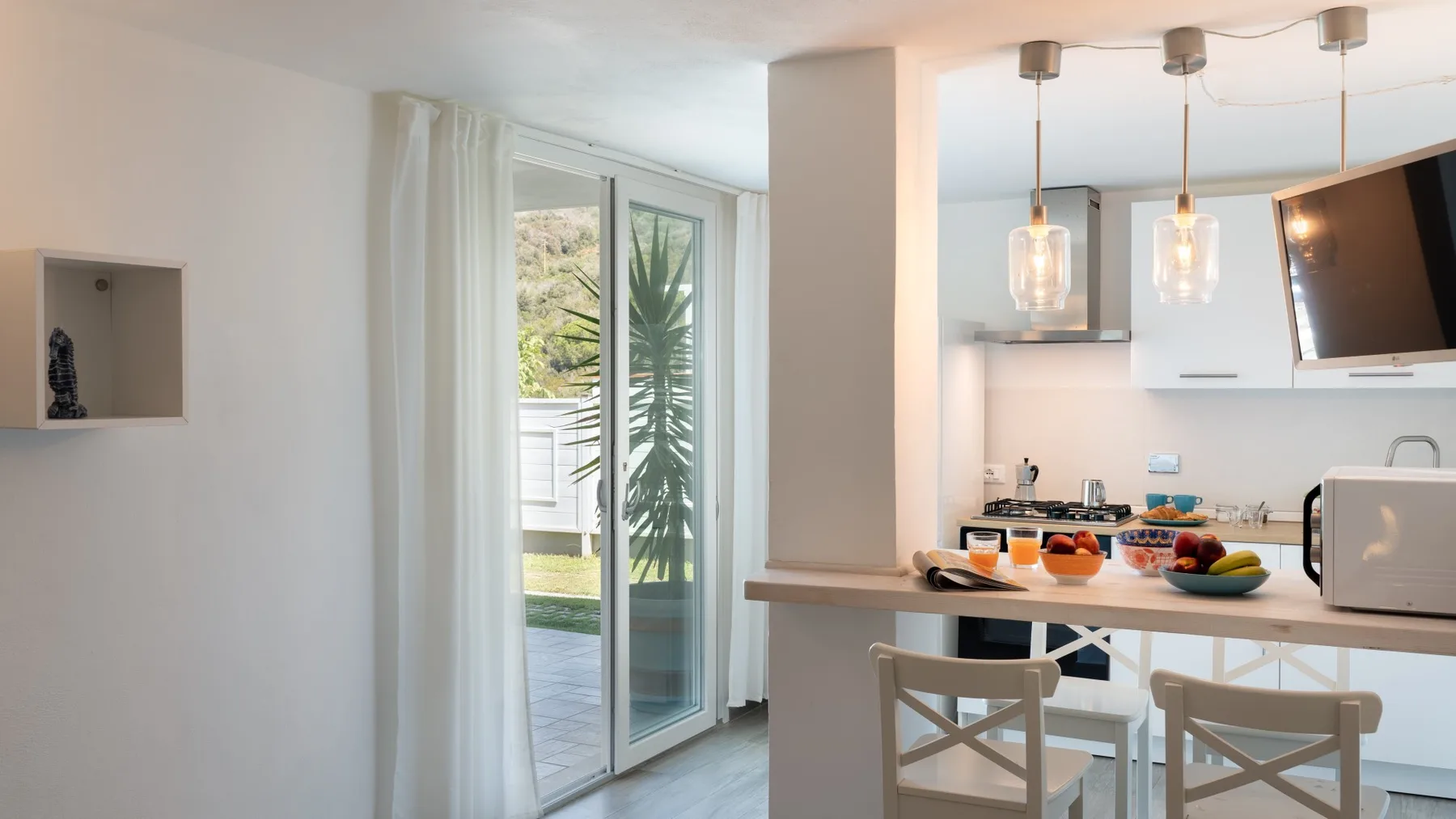 Una cocina luminosa con comedor se abre a un patio mediante puertas de vidrio.