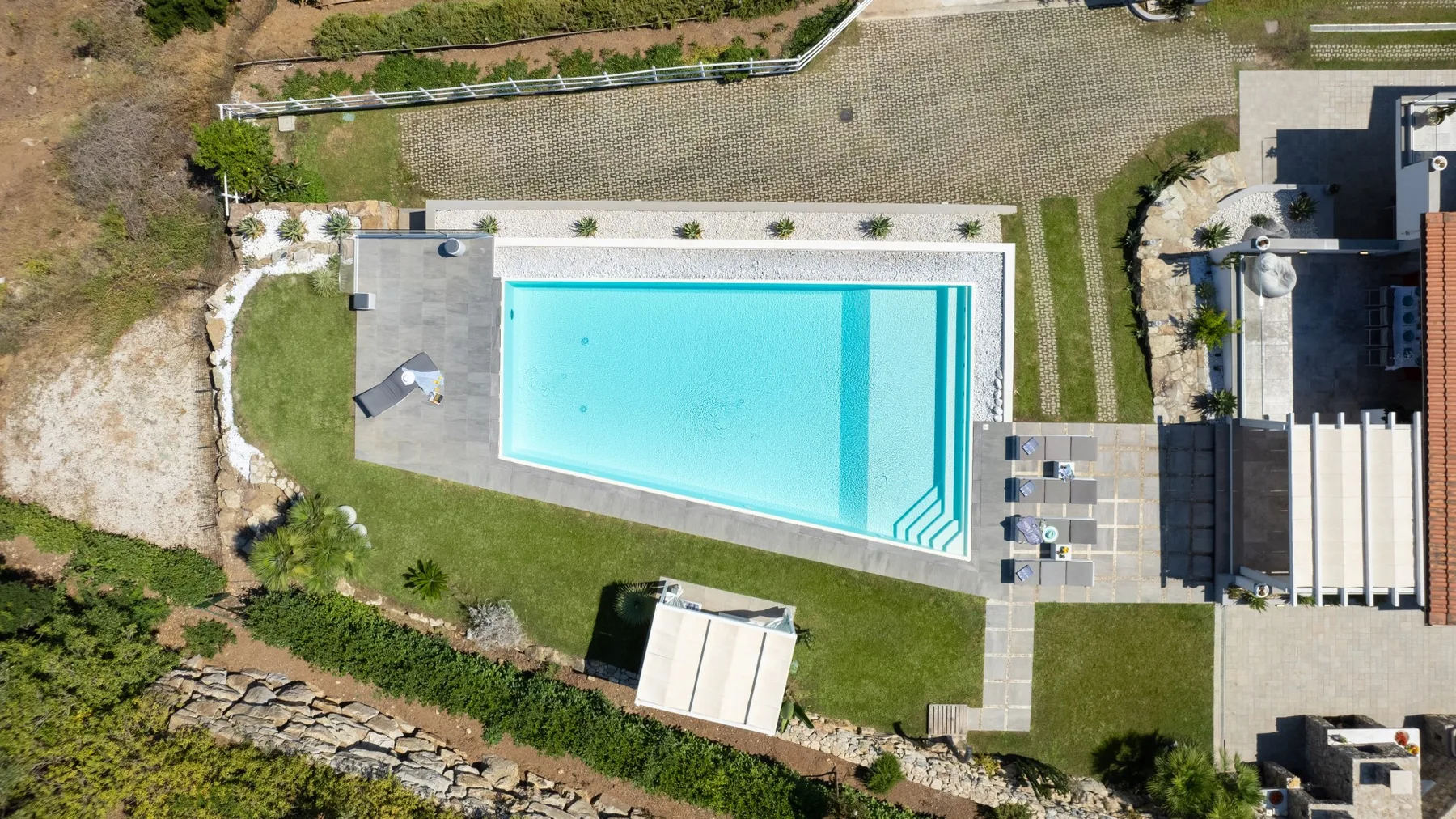 Una vista aérea muestra una piscina turquesa junto a un patio pavimentado.