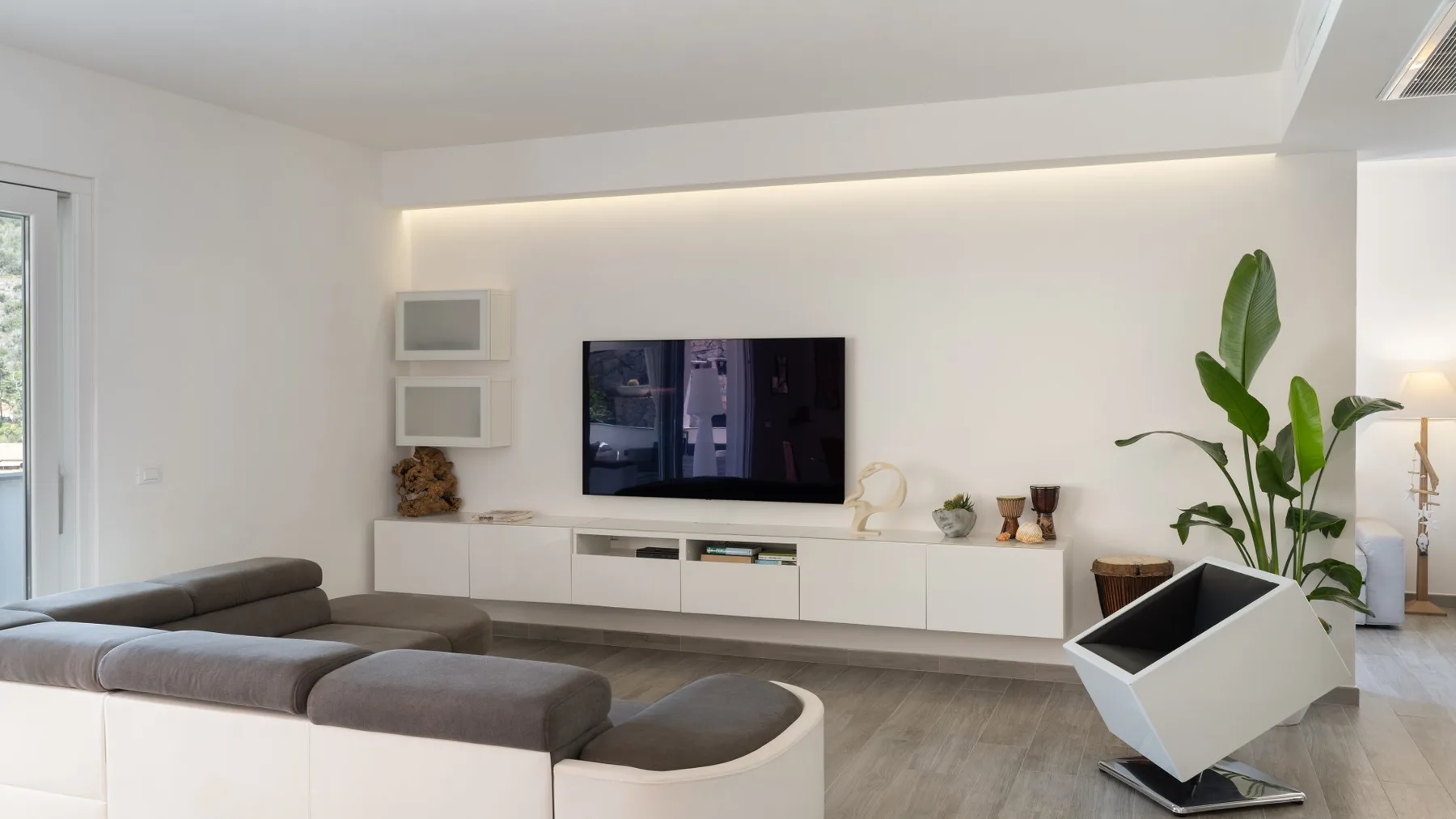 Una sala luminosa con un televisor sobre un mueble bajo blanco.