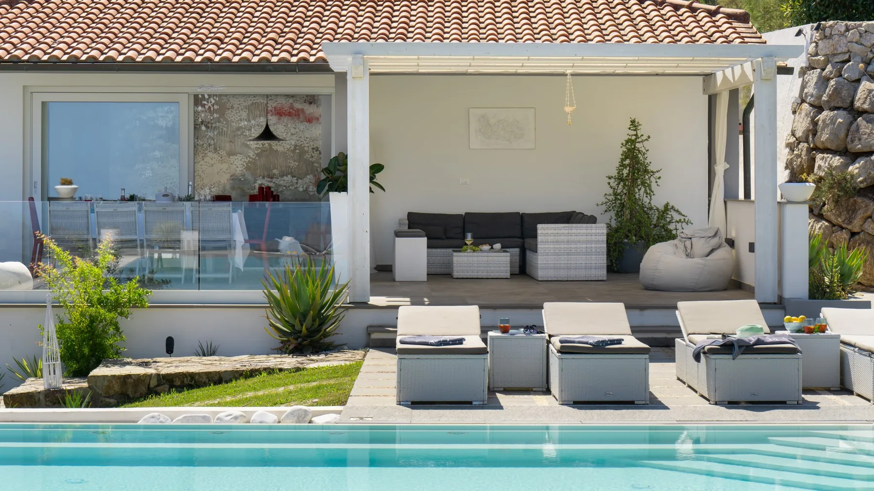 Una piscina al aire libre y un patio con asientos junto a una casa.