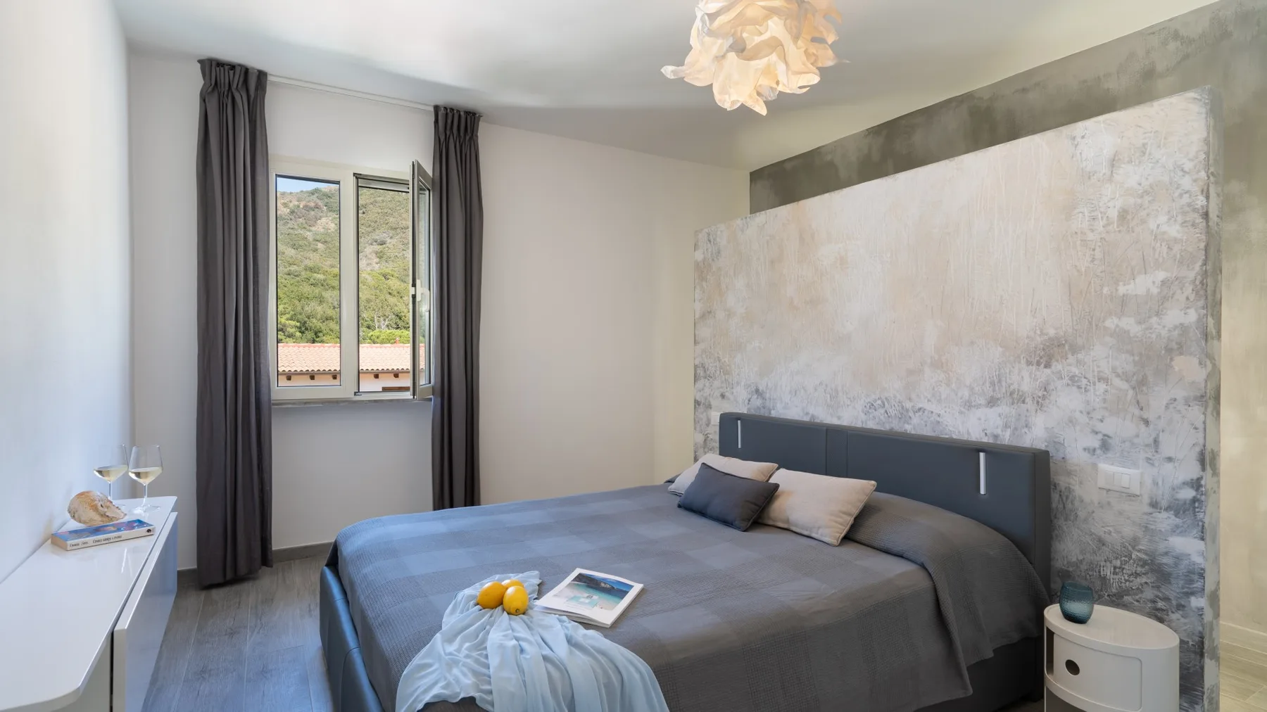 Un dormitorio con una cama tendida y un gran mural abstracto en la pared.
