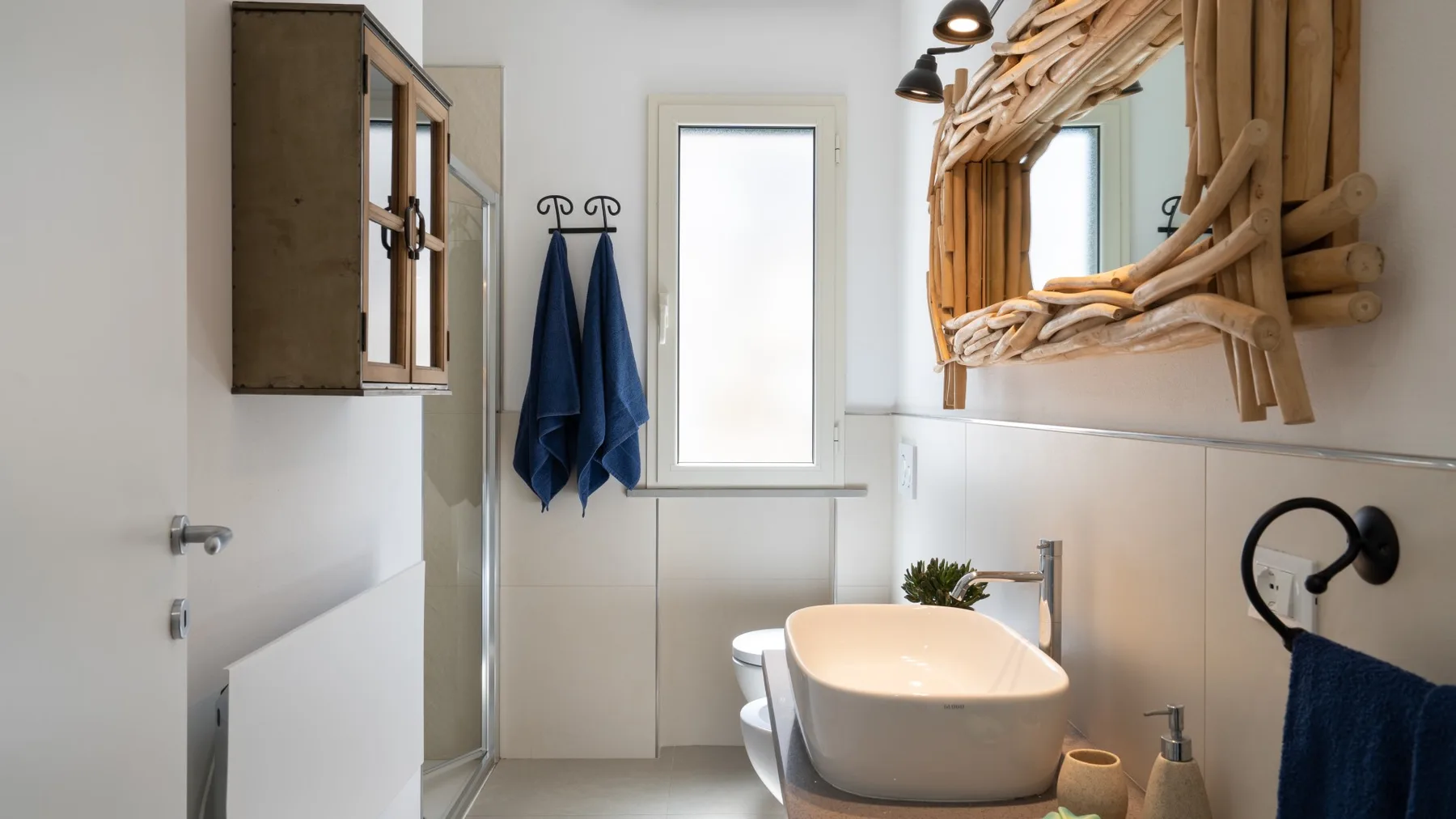 Un baño luminoso con una bañera exenta y un gran espejo con marco rústico.