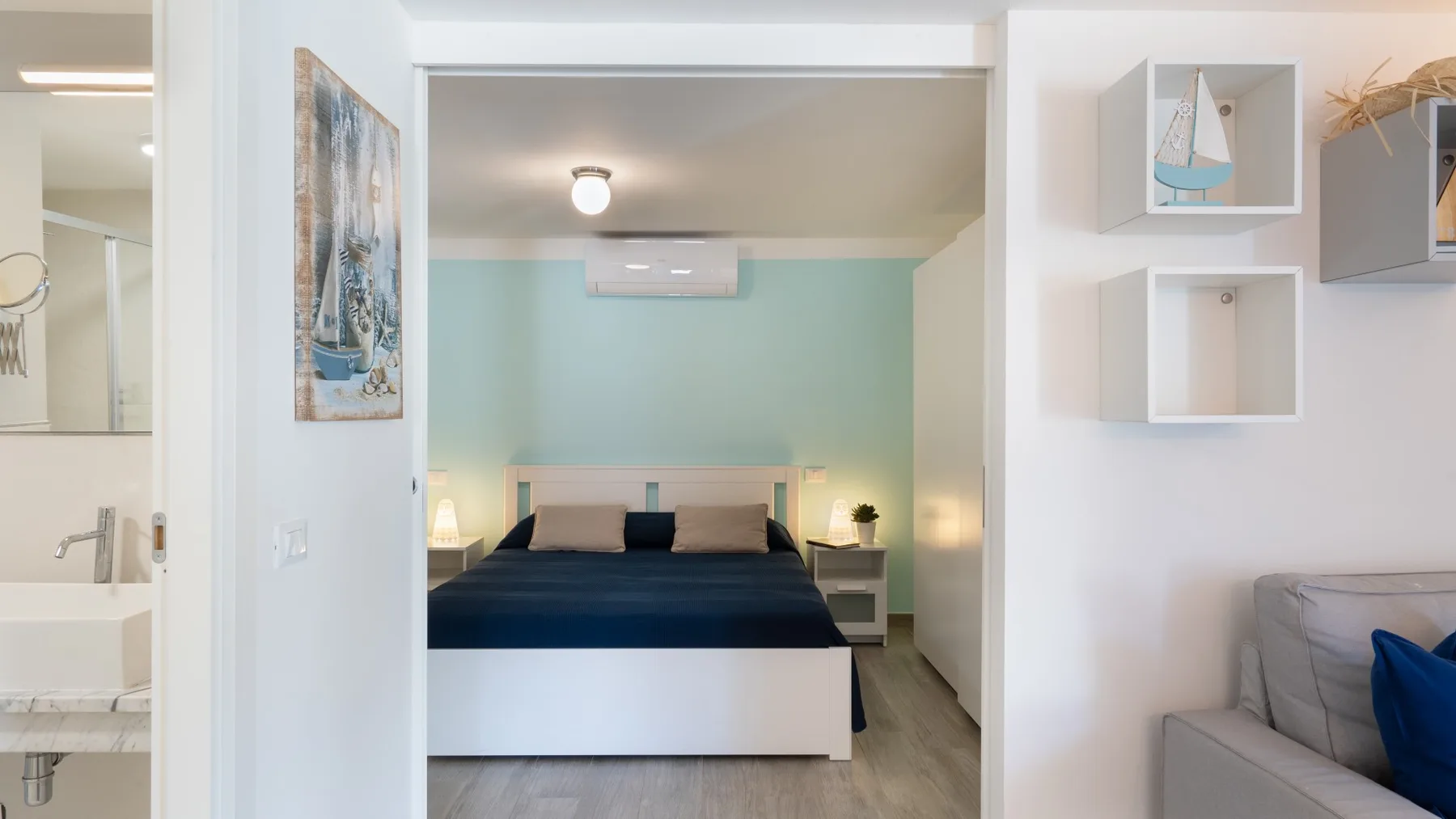 Se ve un dormitorio con una cama y mesas de noche a través de una puerta abierta.