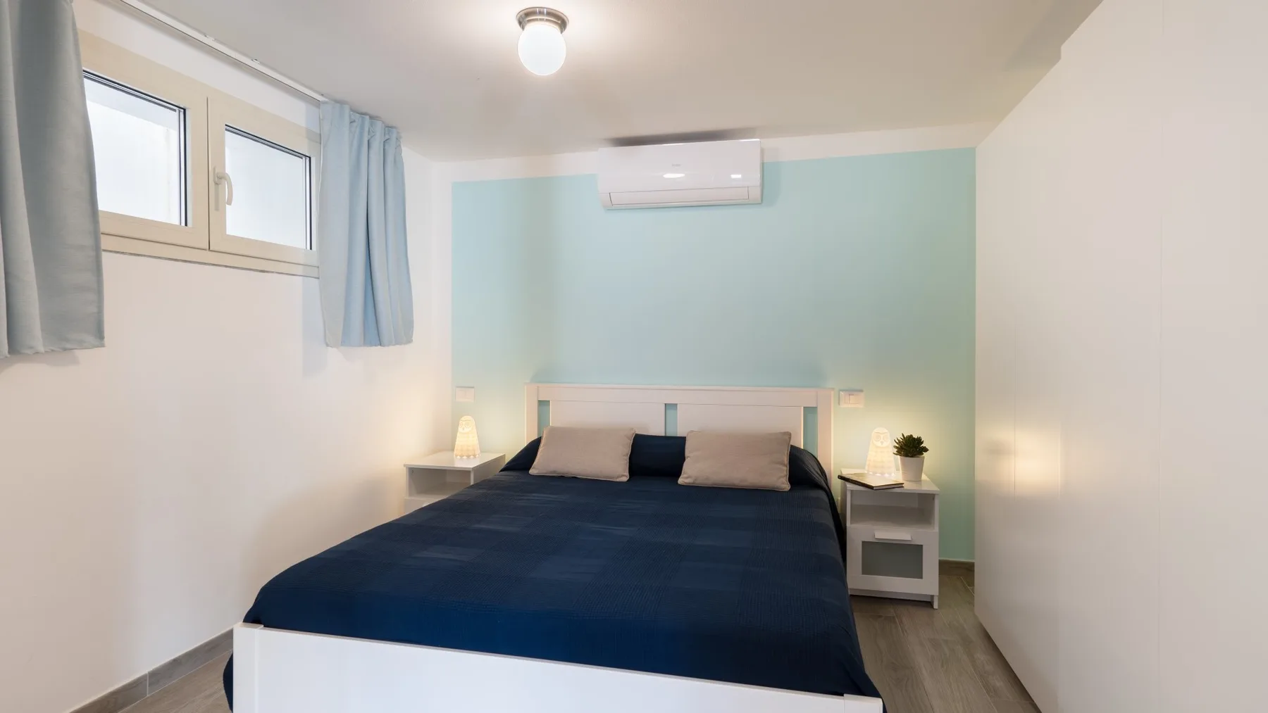 Un dormitorio con una cama debajo de un aire acondicionado de pared.