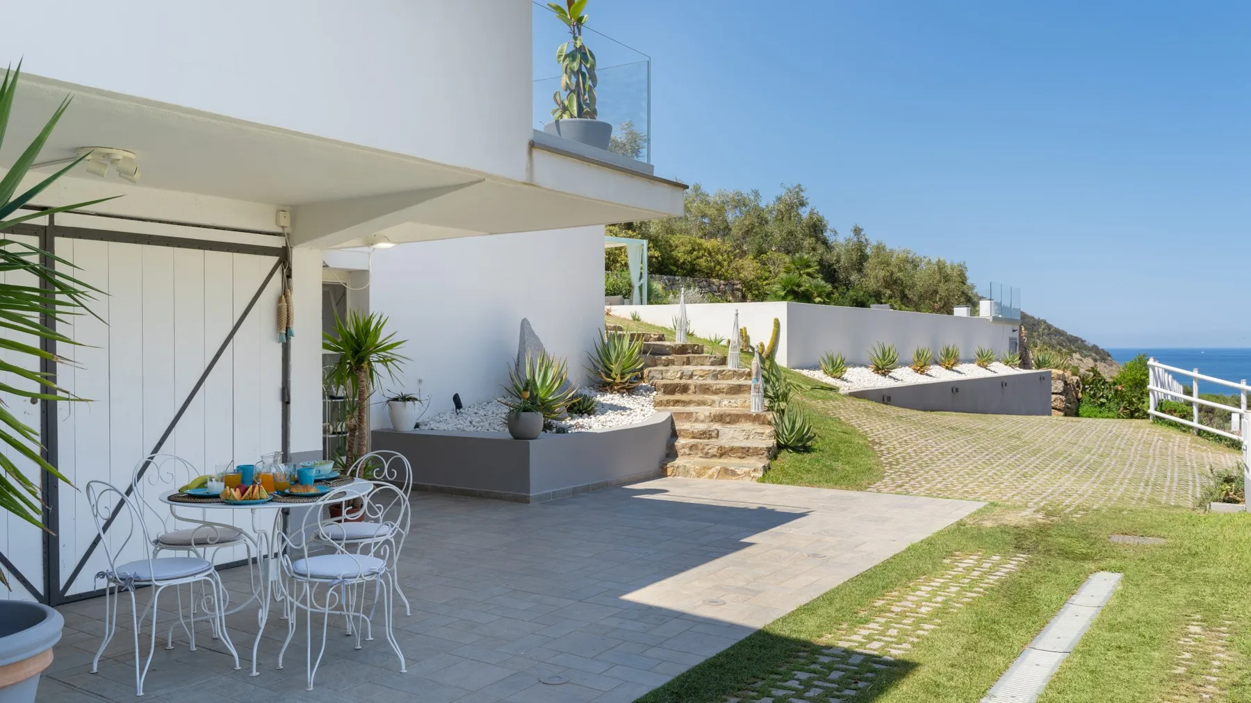 Un patio exterior moderno con comedor, jardineras elevadas y césped.