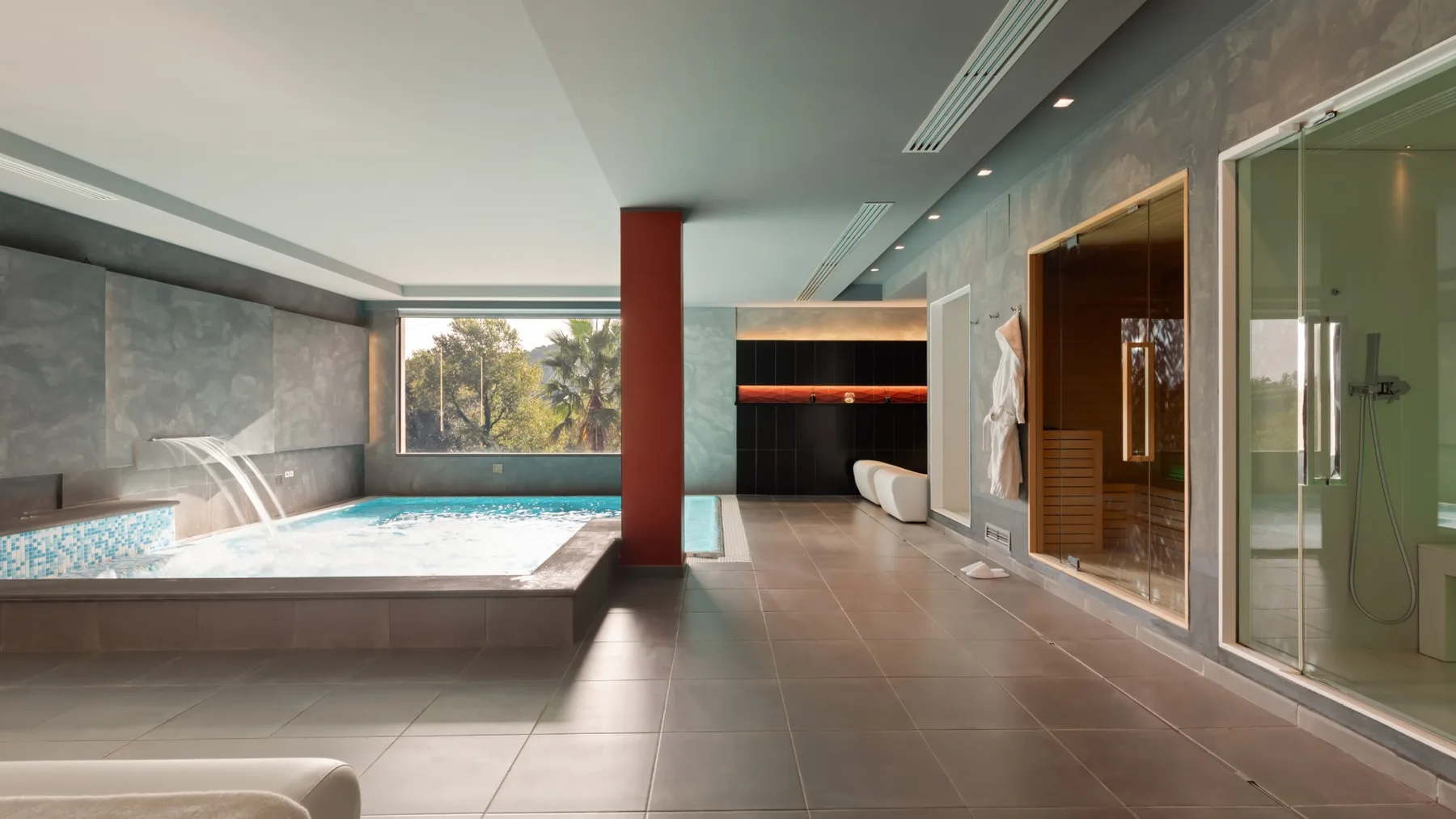A modern indoor pool area with a glass-walled shower and sauna.