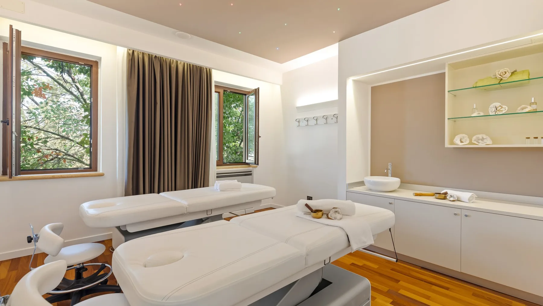 A bright treatment room with padded tables and a wall-mounted sink.
