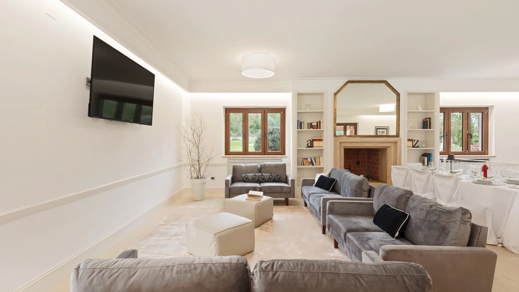 A bright living room with gray seating, a fireplace, and a dining table.