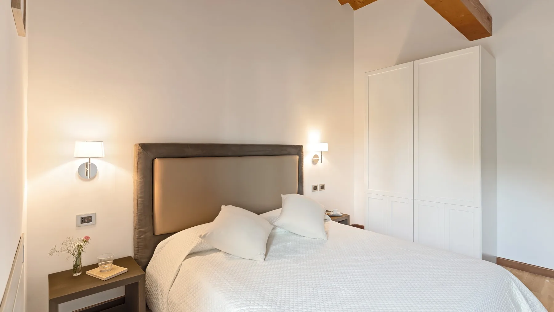 A bedroom with a neatly made bed and a white wardrobe.