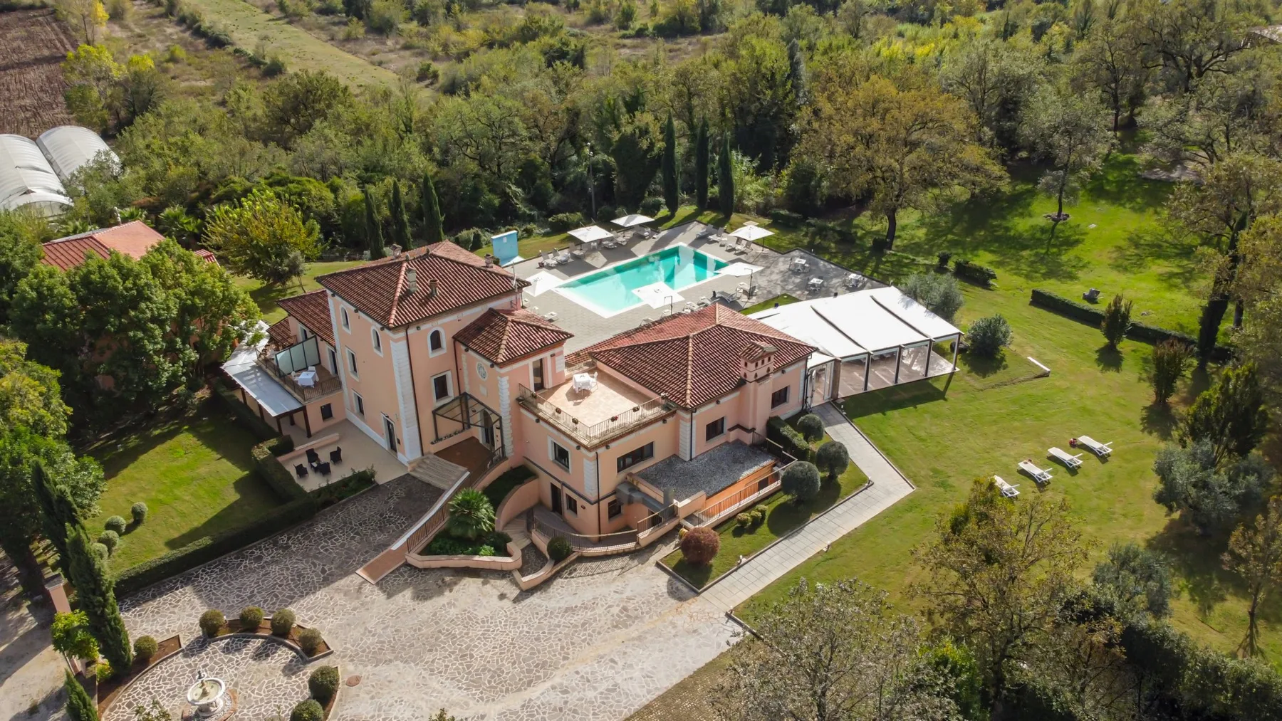 An aerial view of a large house with a swimming pool and surrounding grounds.