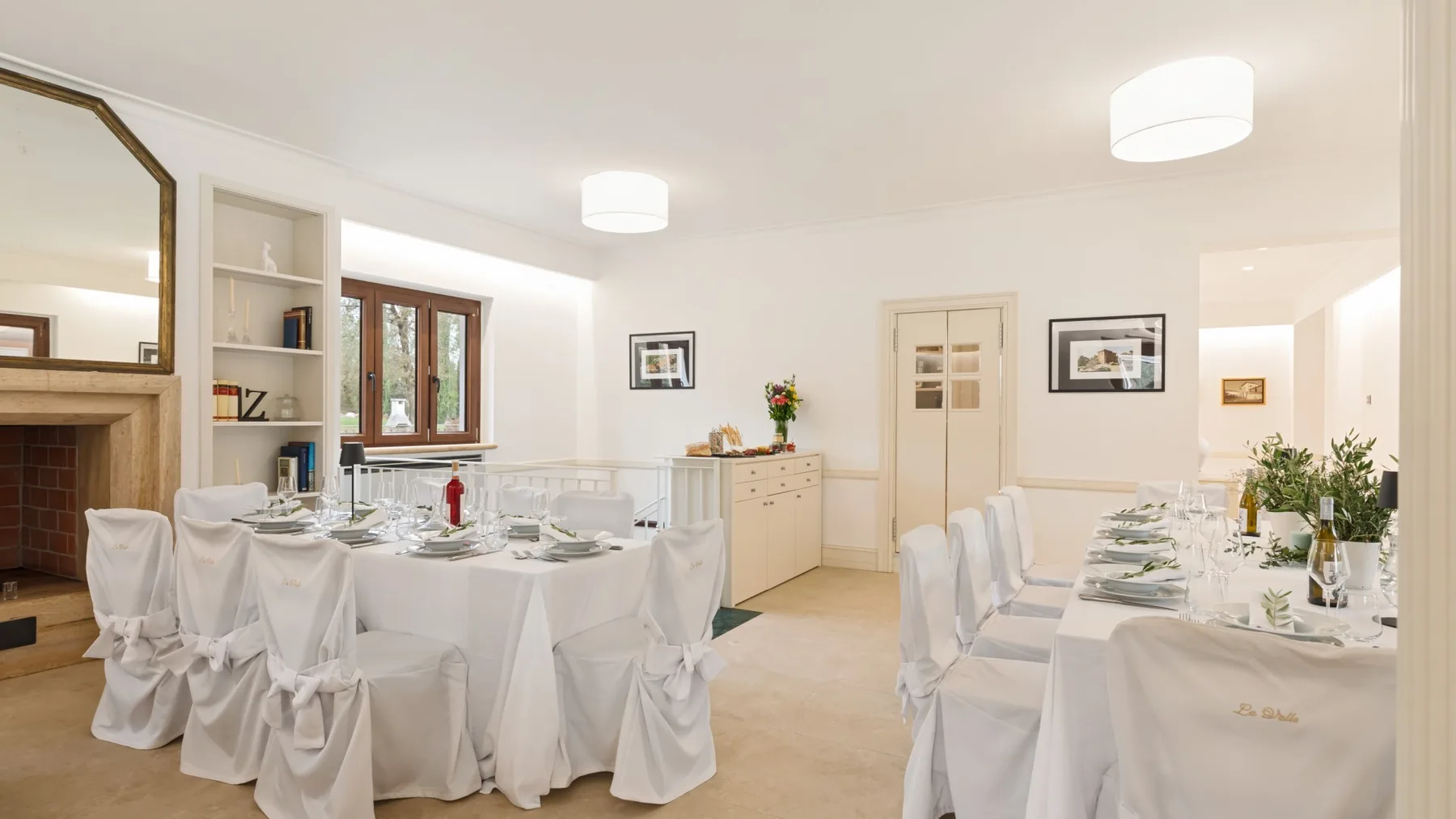 A bright dining room with tables set for a meal and white-covered seating.