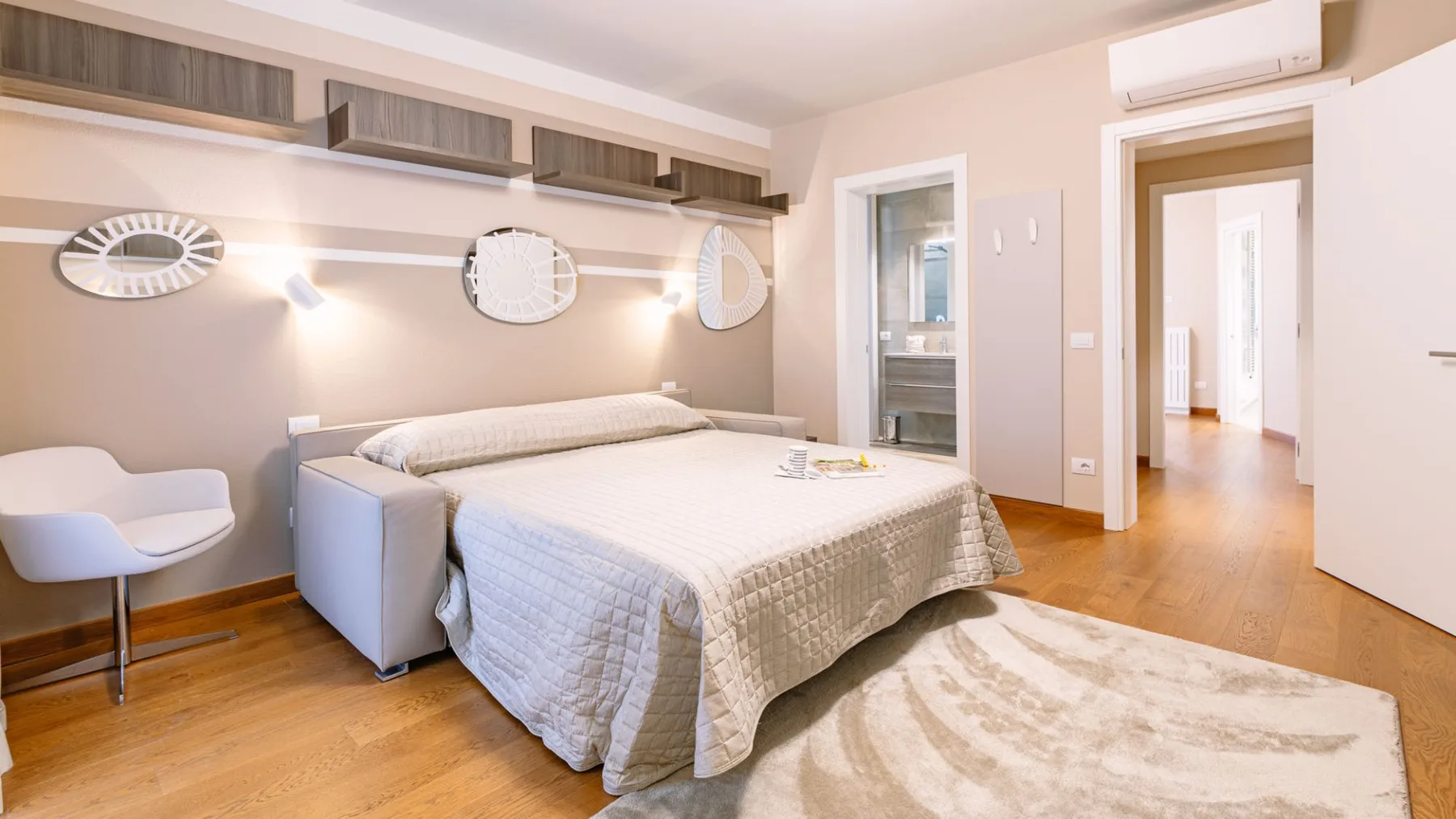 Un dormitorio con una cama, una silla y una alfombra de tonos claros.