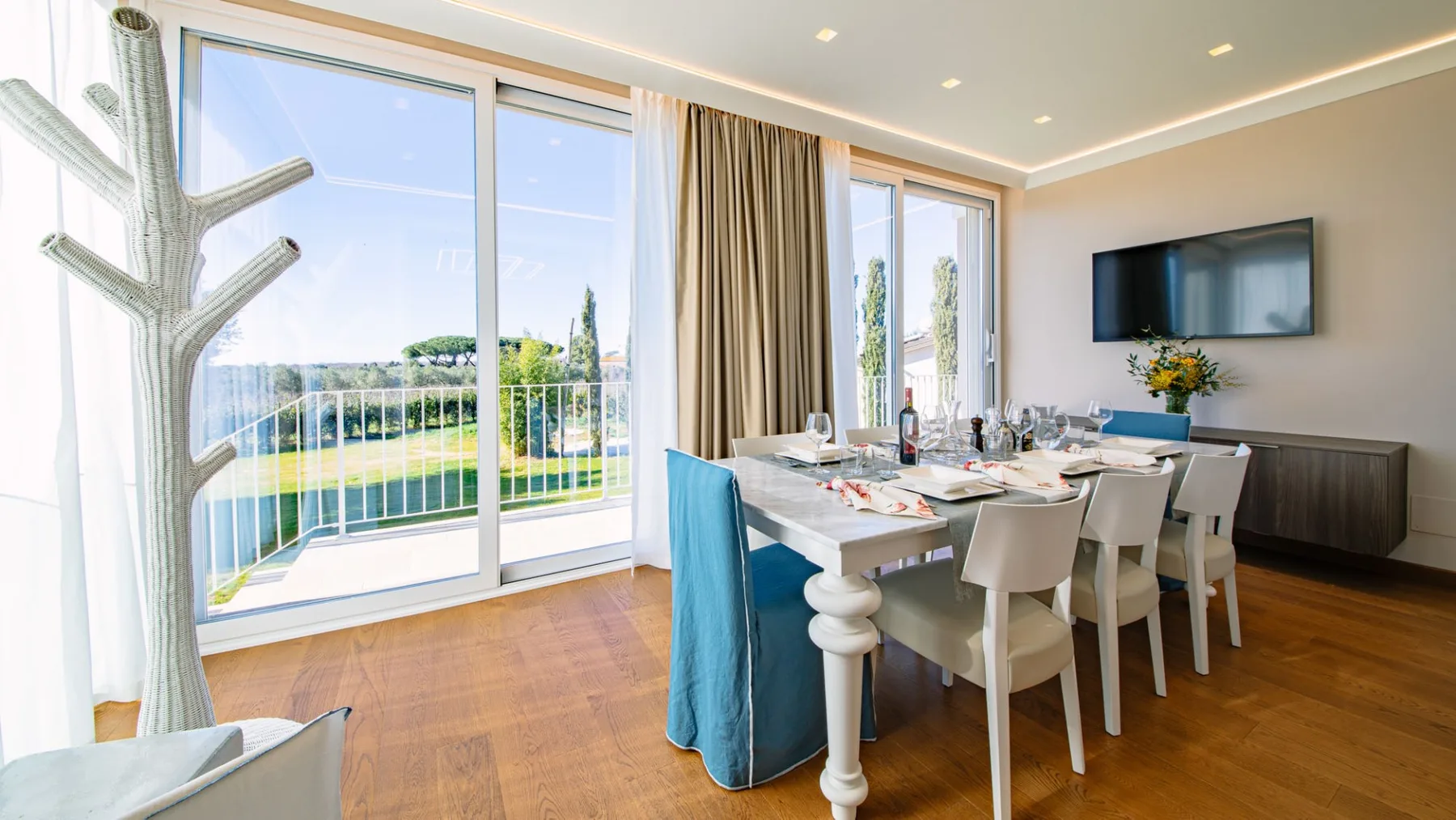 Comedor luminoso con una mesa junto a grandes puertas de vidrio que dan a un balcón.