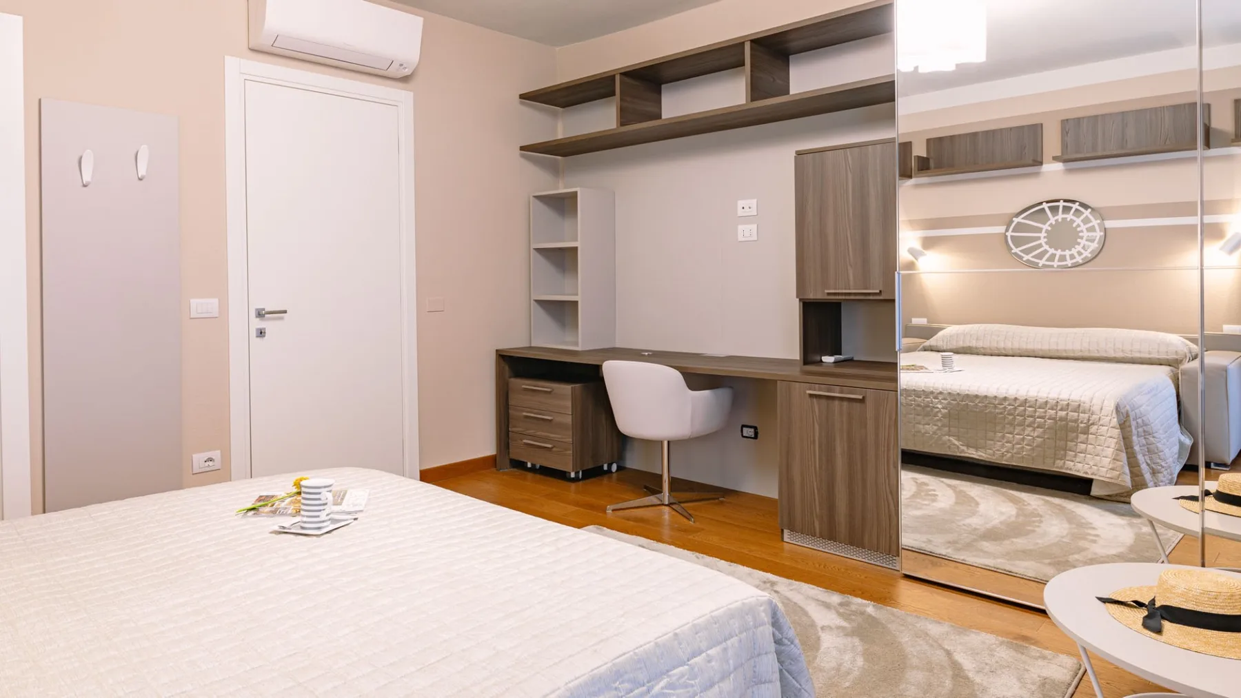 Un dormitorio con una cama, un escritorio y estantes en la pared.