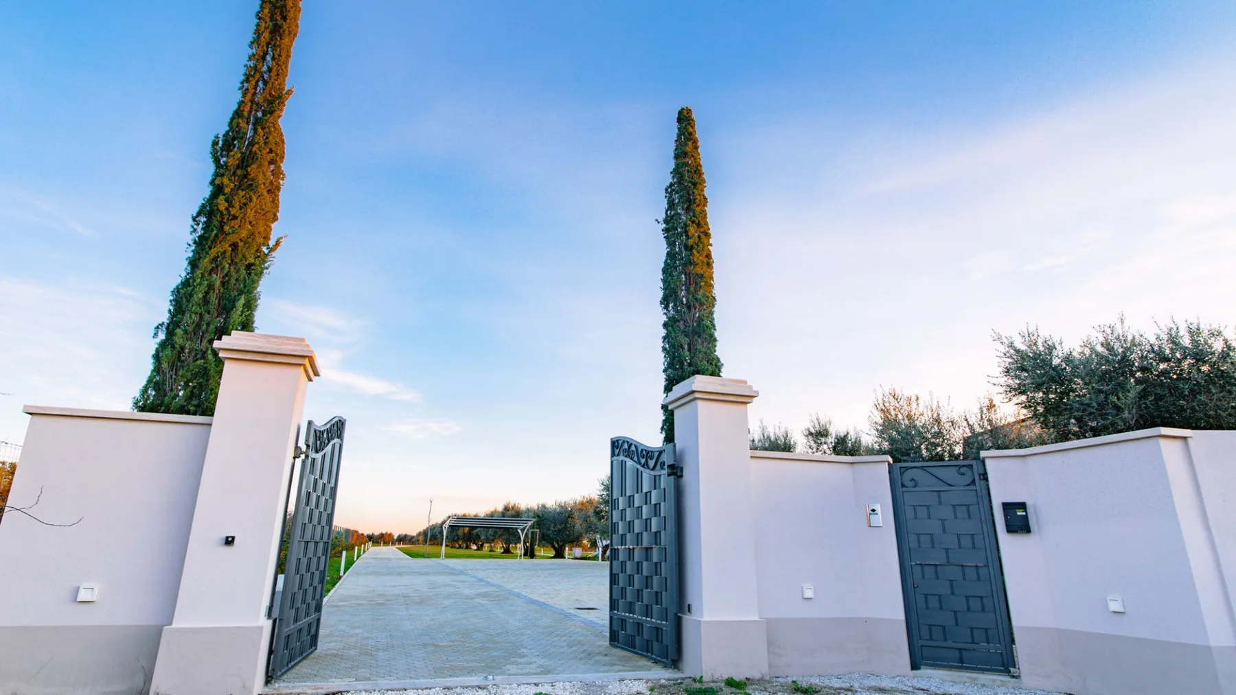 Una puerta de entrada abierta da a un patio exterior pavimentado bajo un cielo despejado.