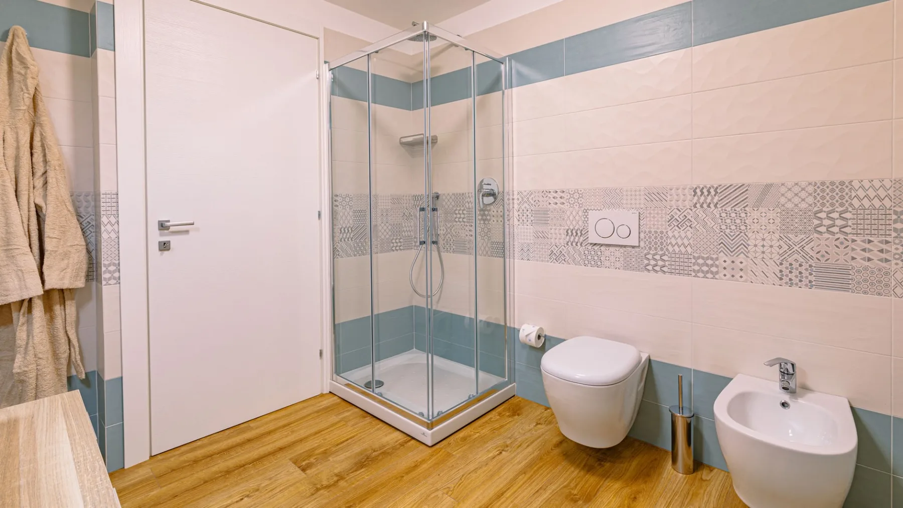 Un baño alicatado con ducha de vidrio, inodoro y lavabo.