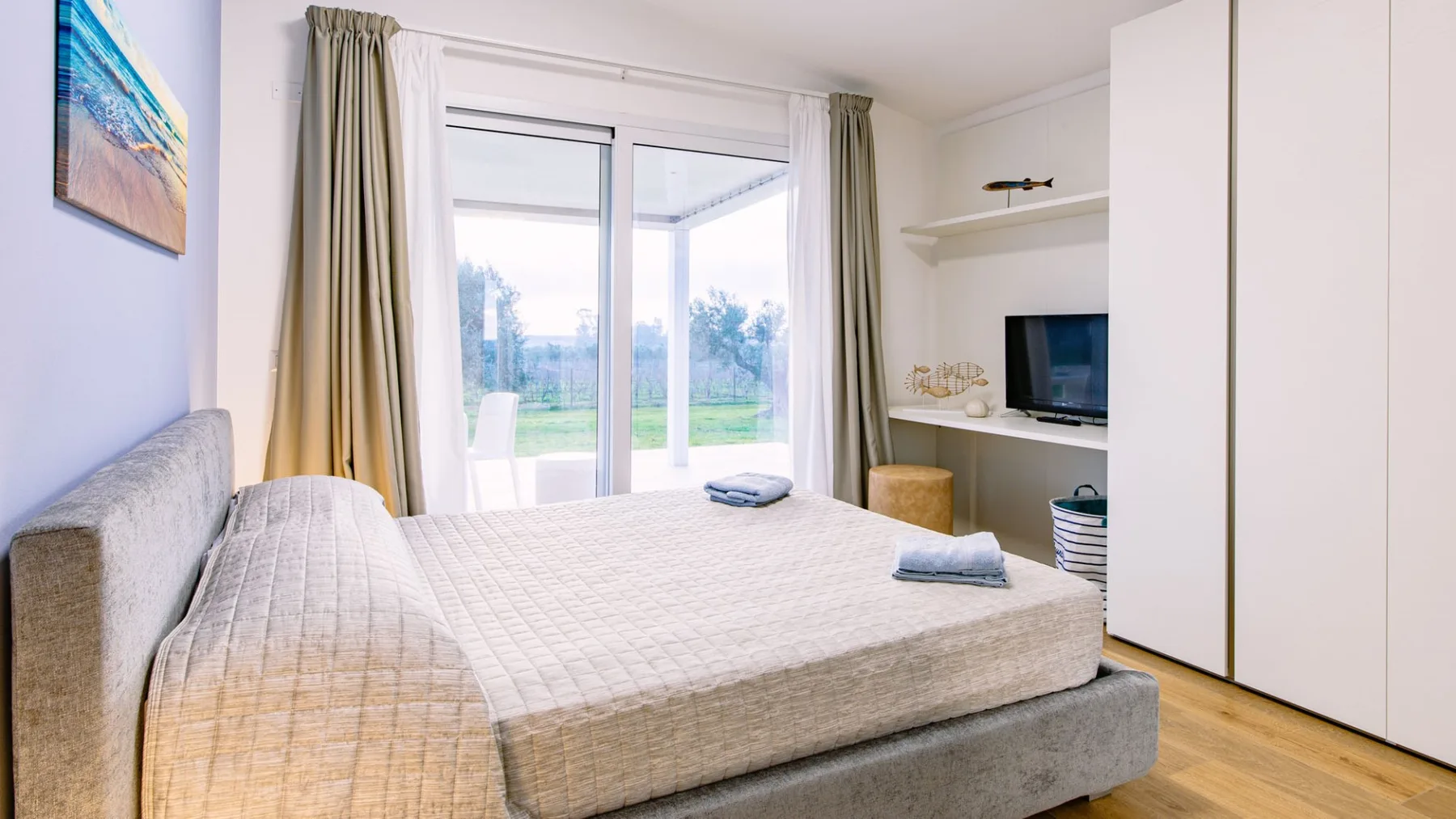 Un dormitorio con una cama junto a grandes puertas de vidrio y cortinas.