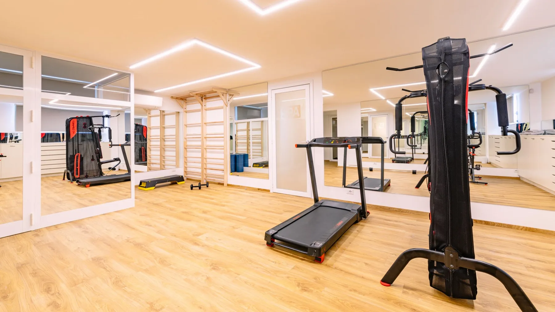 Una sala de ejercicio luminosa con cintas de correr y otros equipos de entrenamiento.