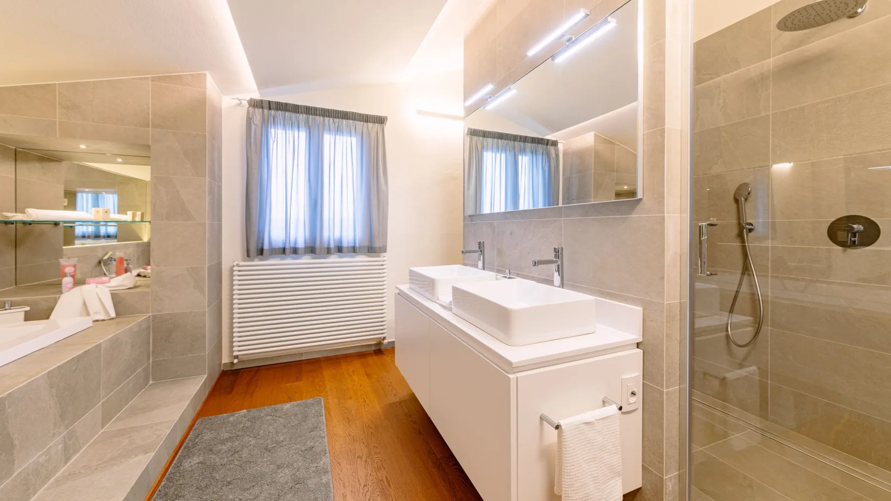 Un baño luminoso con lavabo, espejo y ducha de vidrio.
