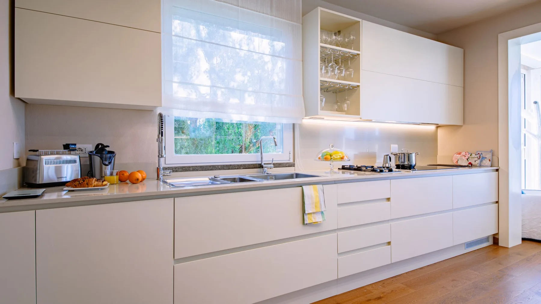 Una cocina luminosa con gabinetes blancos, encimera y una ventana sobre el fregadero.