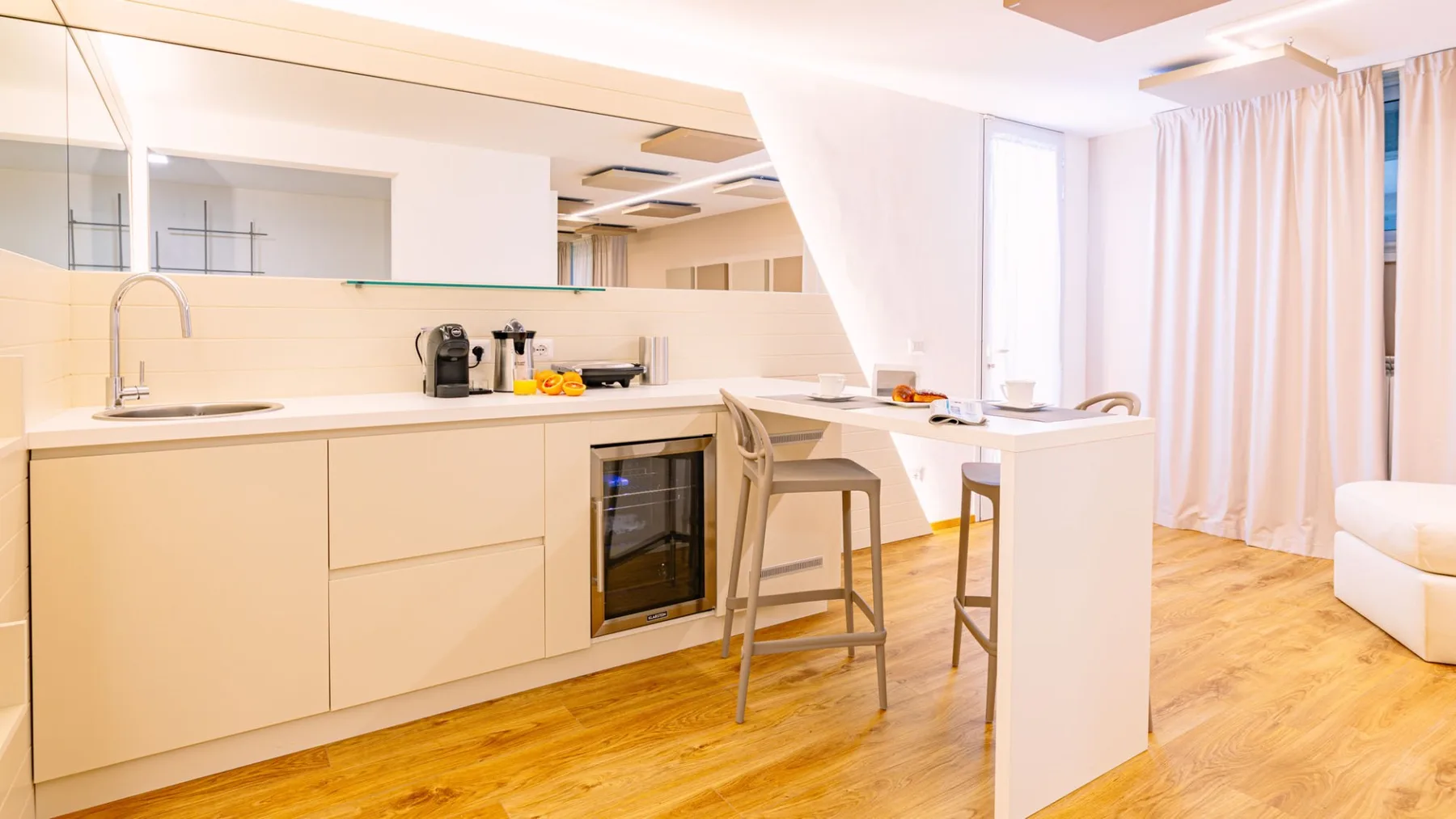 Una cocina luminosa con una encimera y asientos junto a cortinas largas.