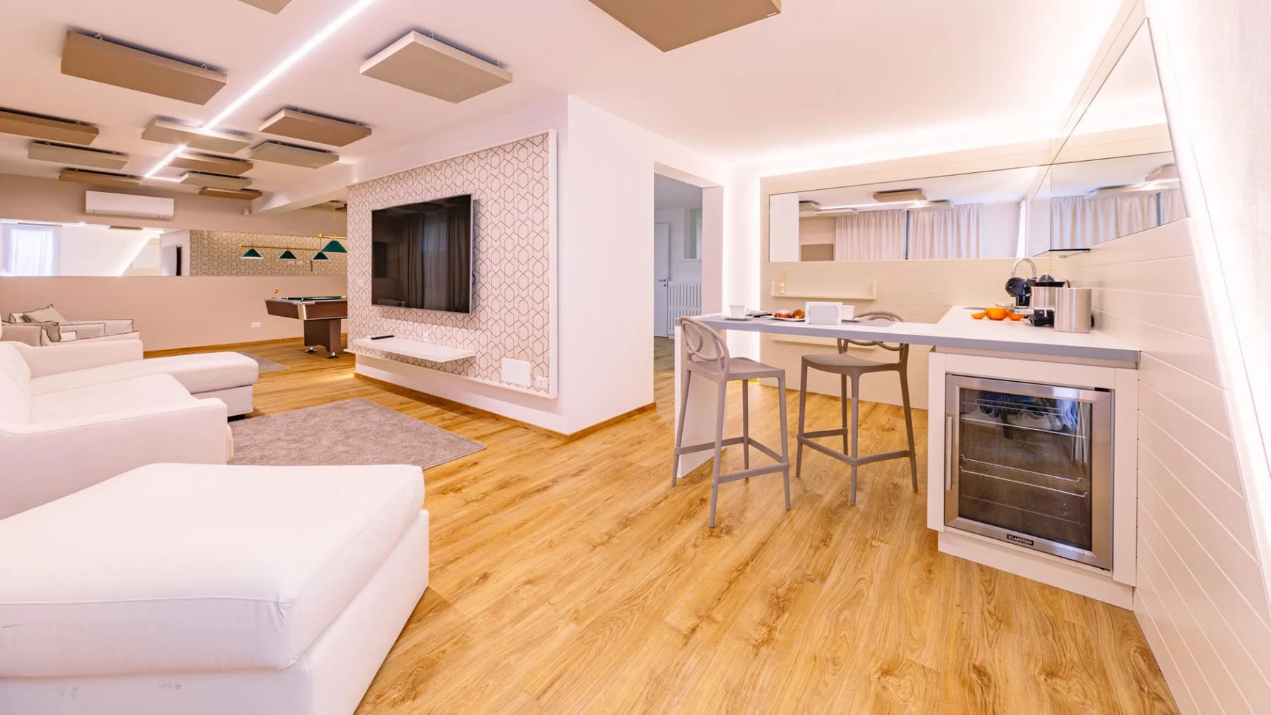 Una luminosa sala de estar diáfana con asientos blancos y una barra de comedor.