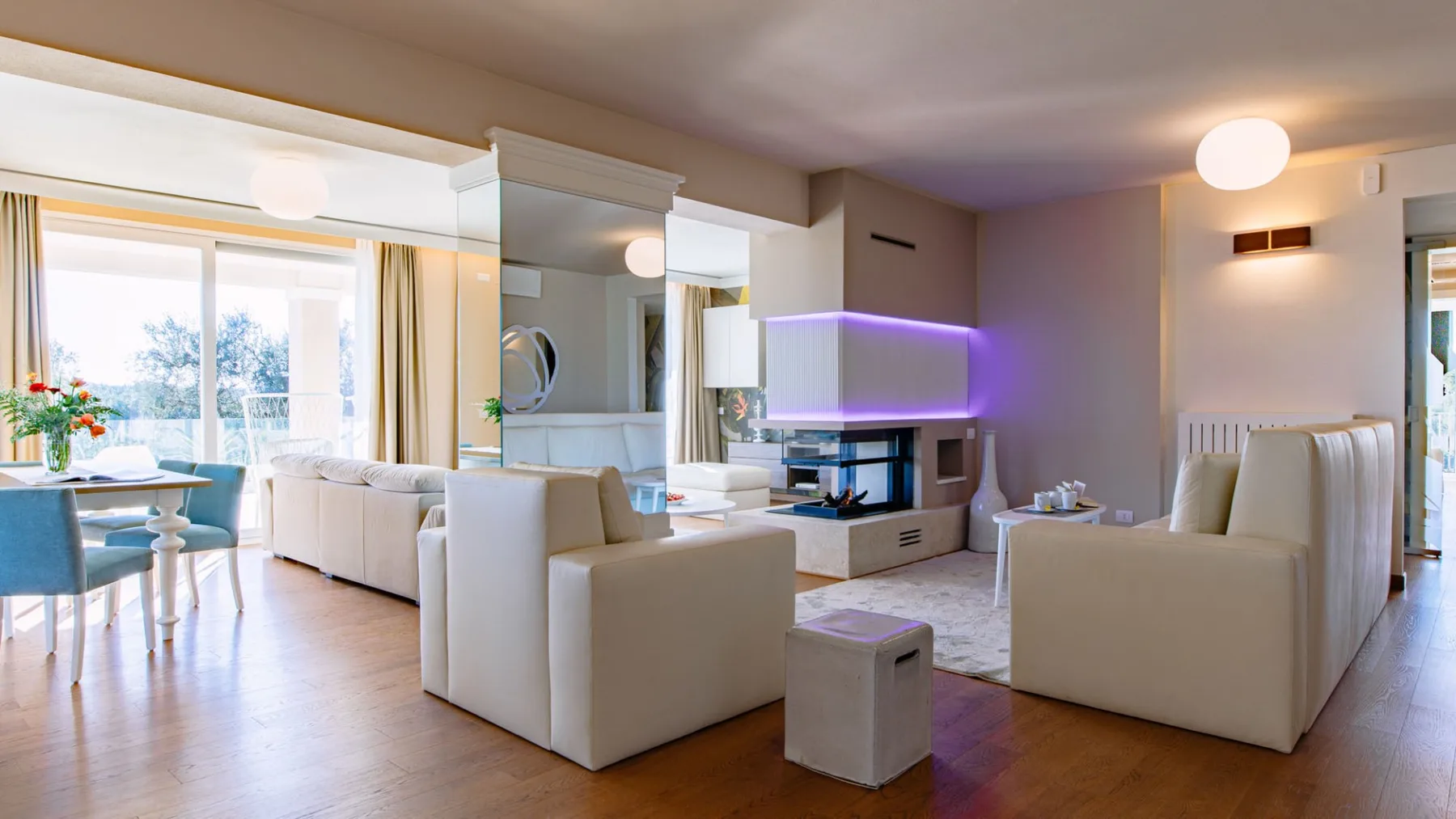 Una sala luminosa con asientos, un televisor y grandes ventanas.