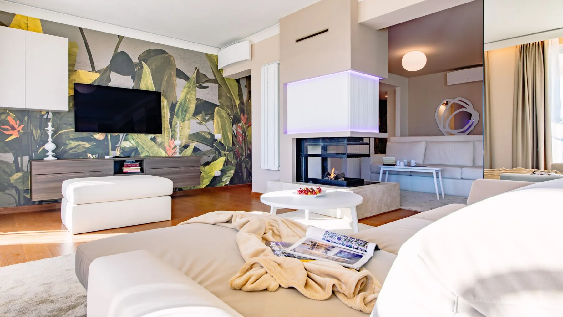 Una sala de estar moderna con asientos blancos, una mesa baja y una chimenea.