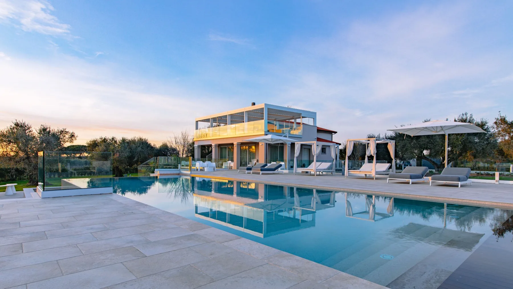 Una casa moderna está junto a una piscina y un patio pavimentado.