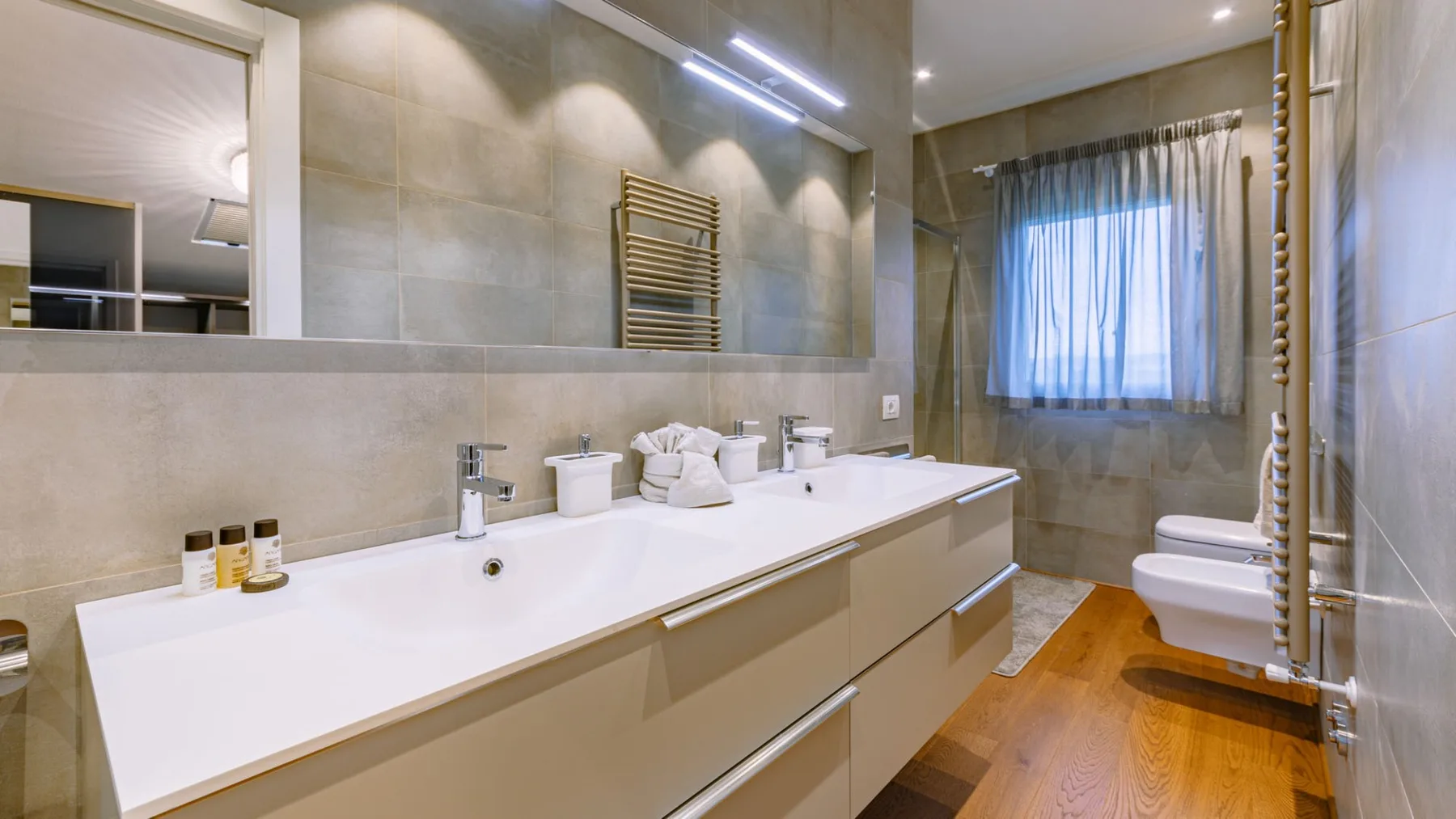 Un baño moderno con un tocador largo, lavabo y ventana.