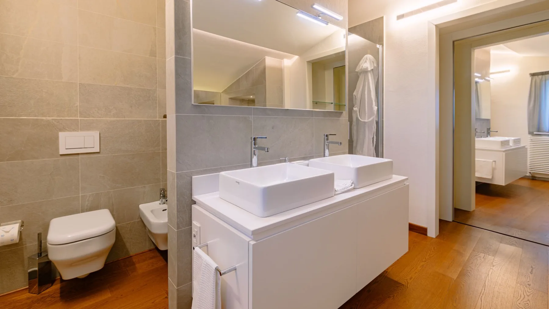 Un baño luminoso con lavabo doble y un inodoro.