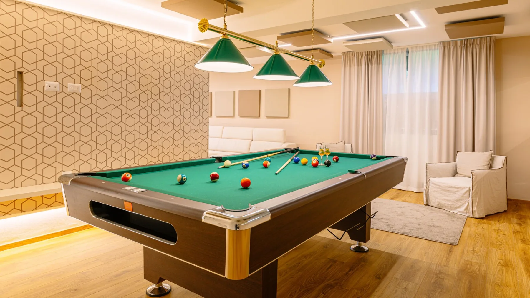 Una sala de billar con una mesa bajo lámparas colgantes verdes.