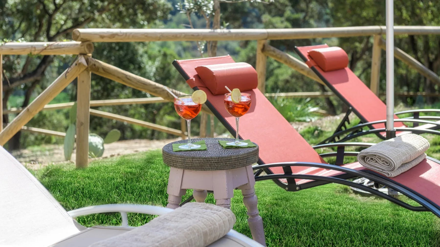 Zona de descanso al aire libre con asientos reclinables y bebidas sobre una mesa pequeña.
