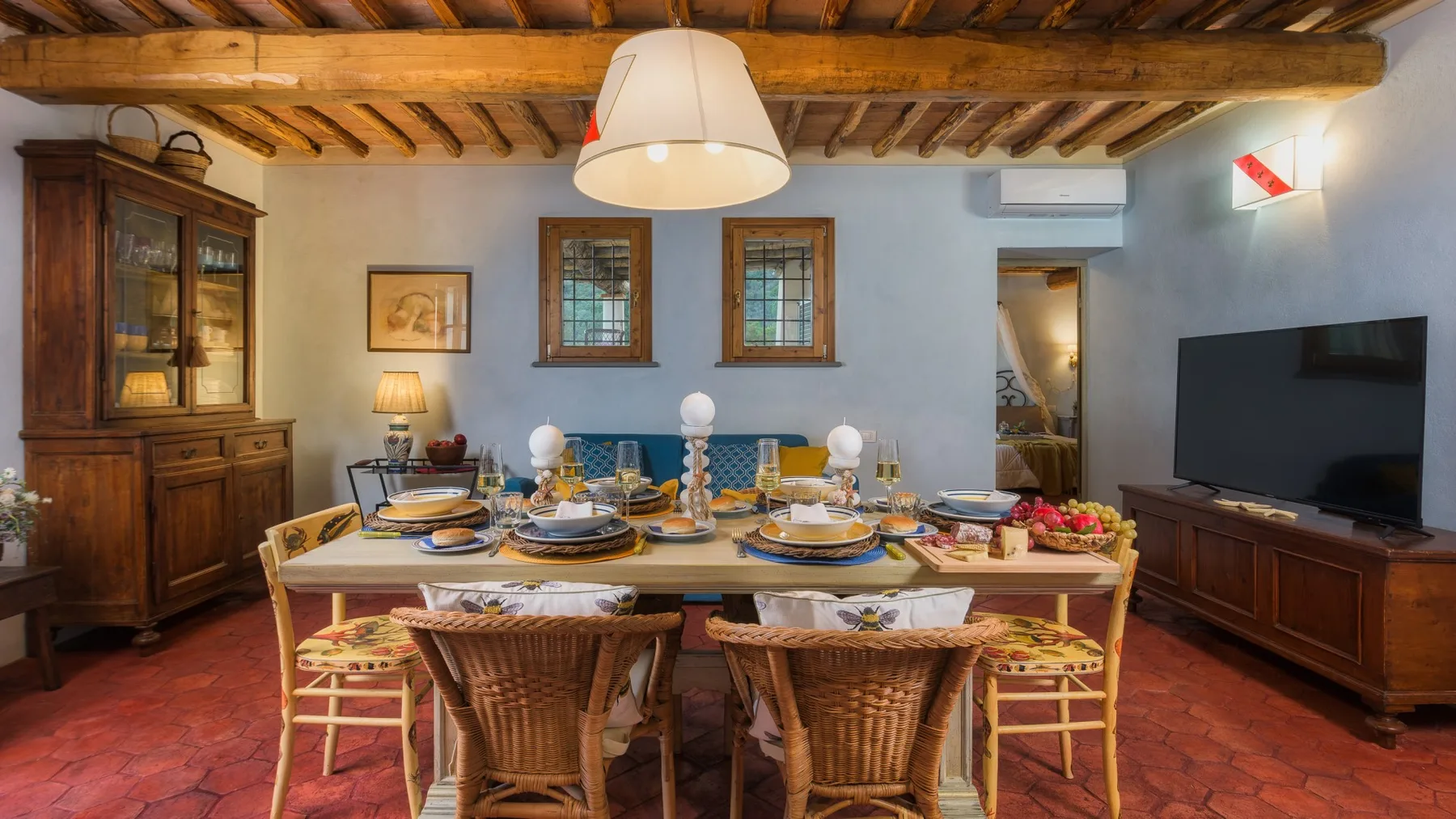 Un comedor con una mesa larga preparada para una comida bajo vigas de madera a la vista.