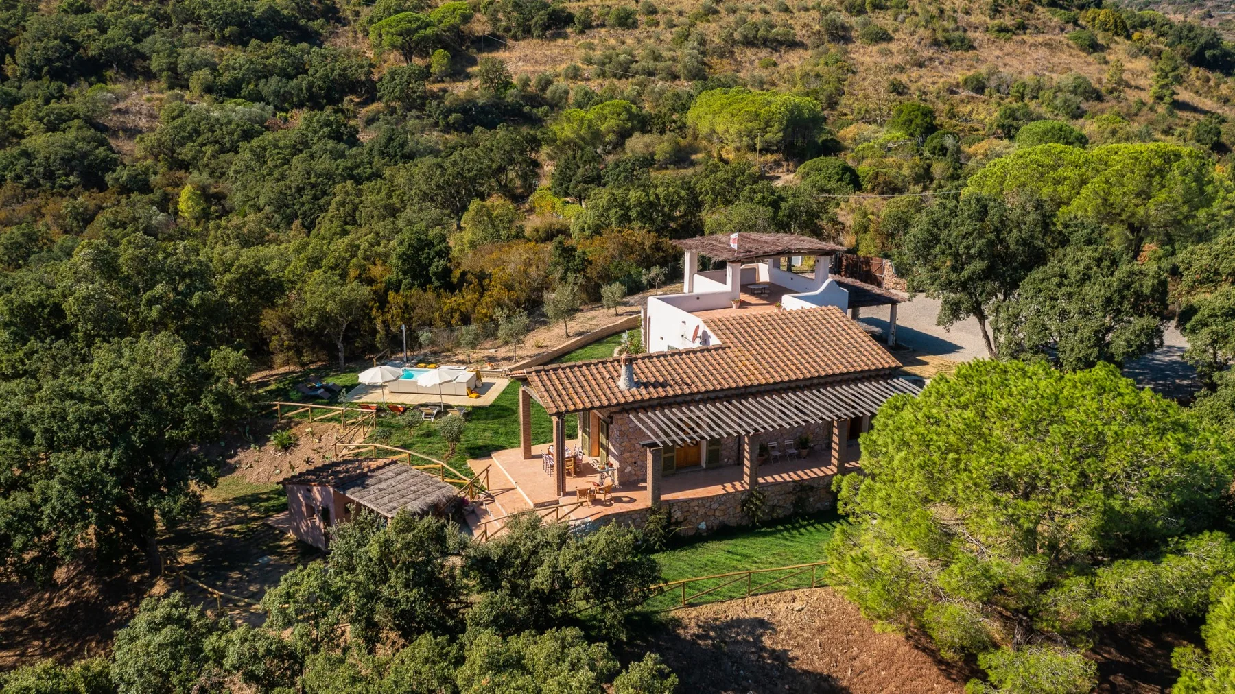 Vista aérea de una casa con techo de color terracota entre árboles y vegetación.