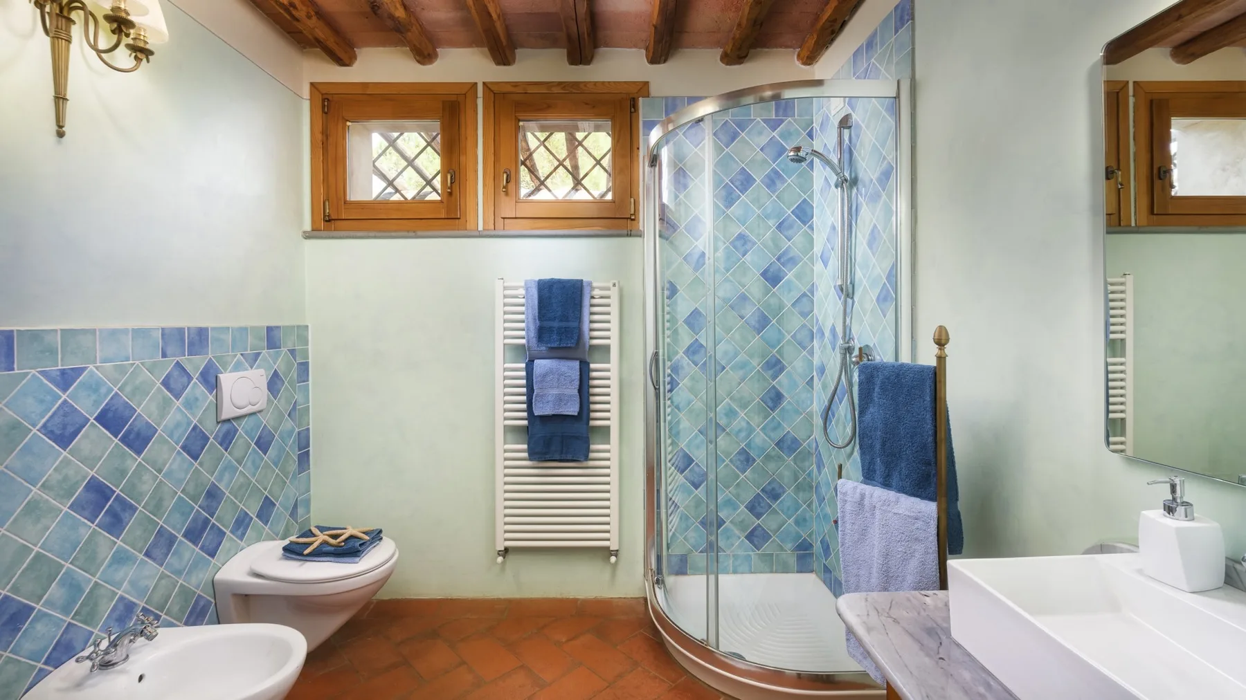 Un baño con azulejos, ducha curva de vidrio, lavabo e inodoro.