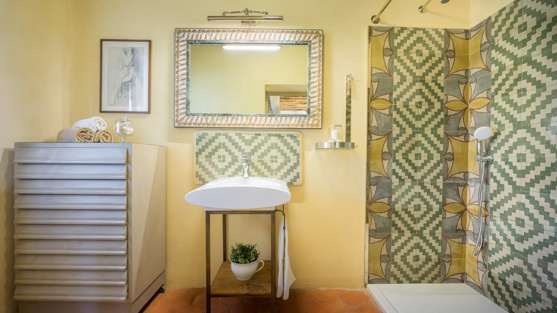 Un baño con lavabo de pedestal y cortina de ducha estampada.