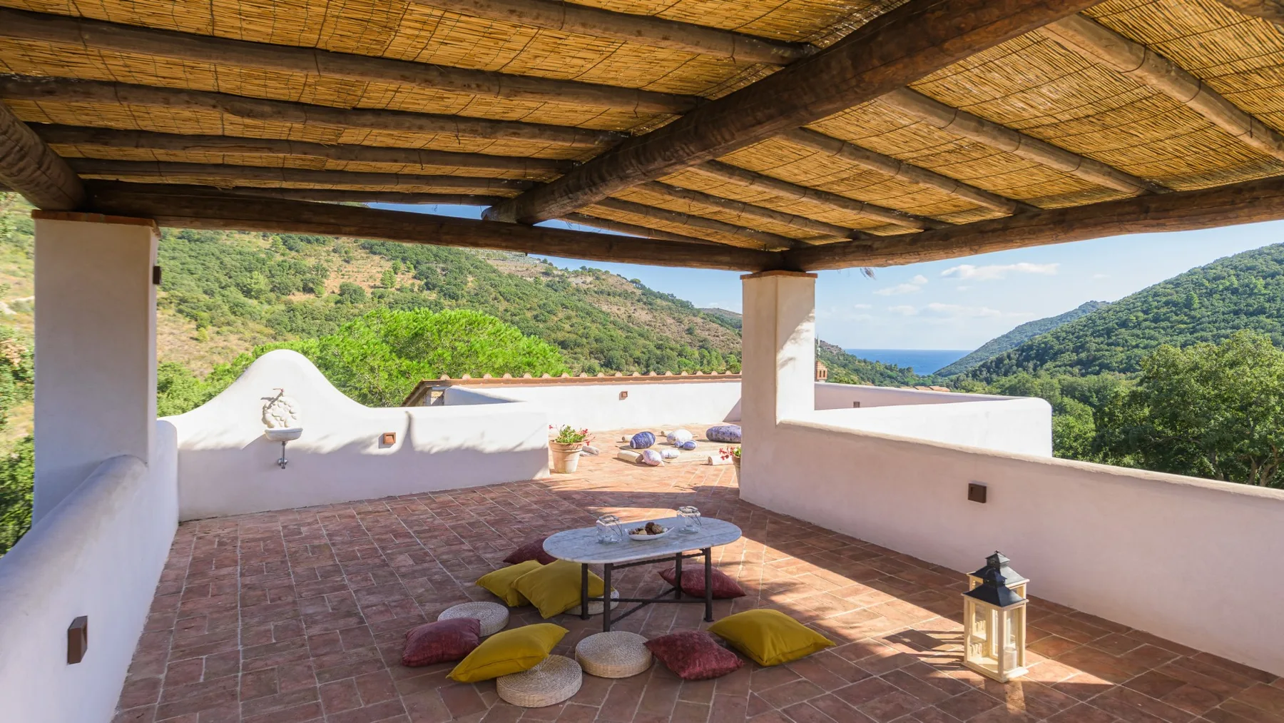 Una terraza exterior cubierta con suelo de baldosas y vistas a colinas verdes.