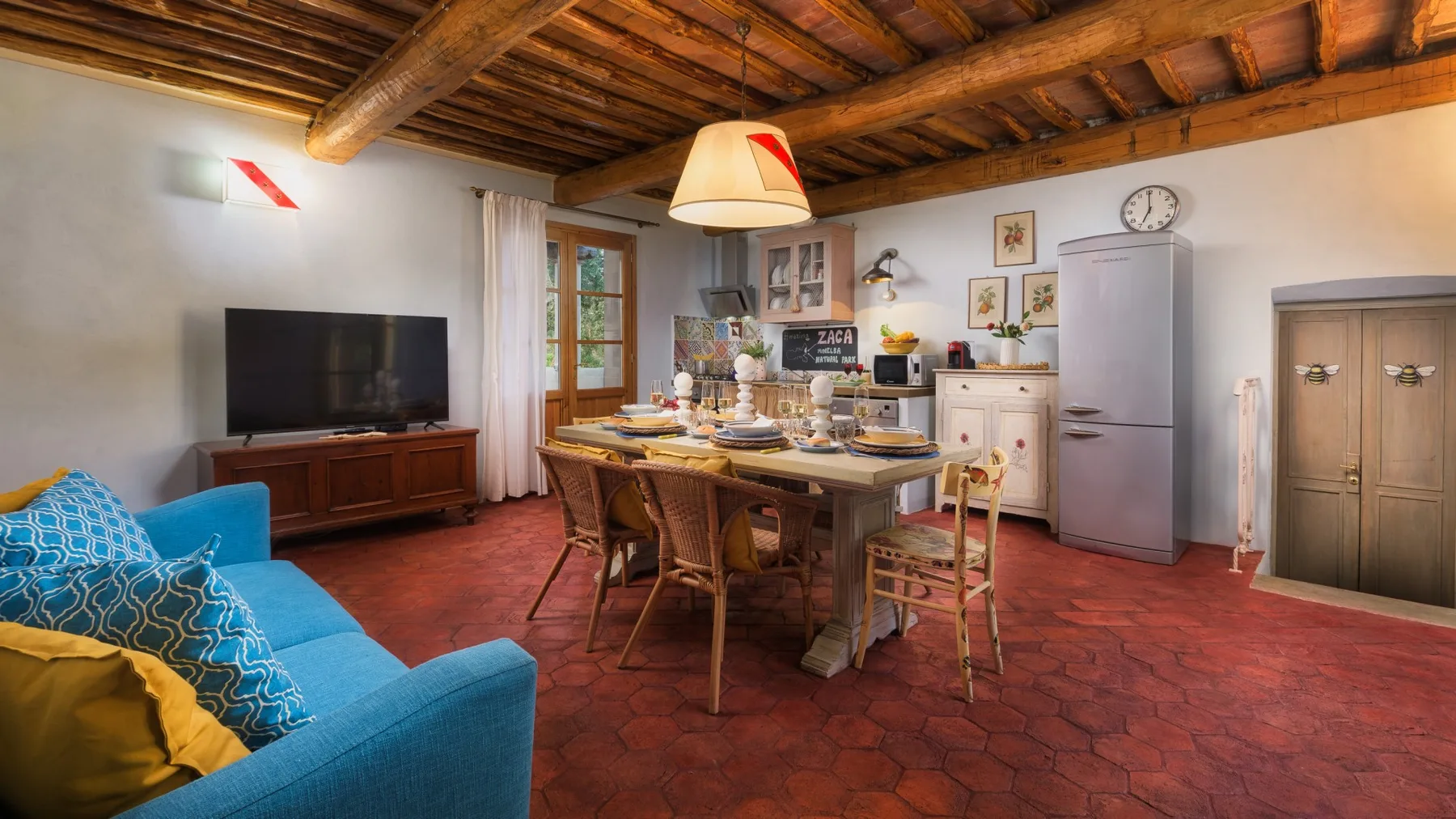 Una sala rústica con comedor, sofá azul y mesa de madera.