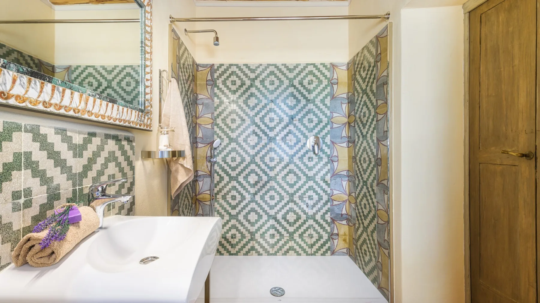 Un baño con azulejos estampados, lavabo y ducha.