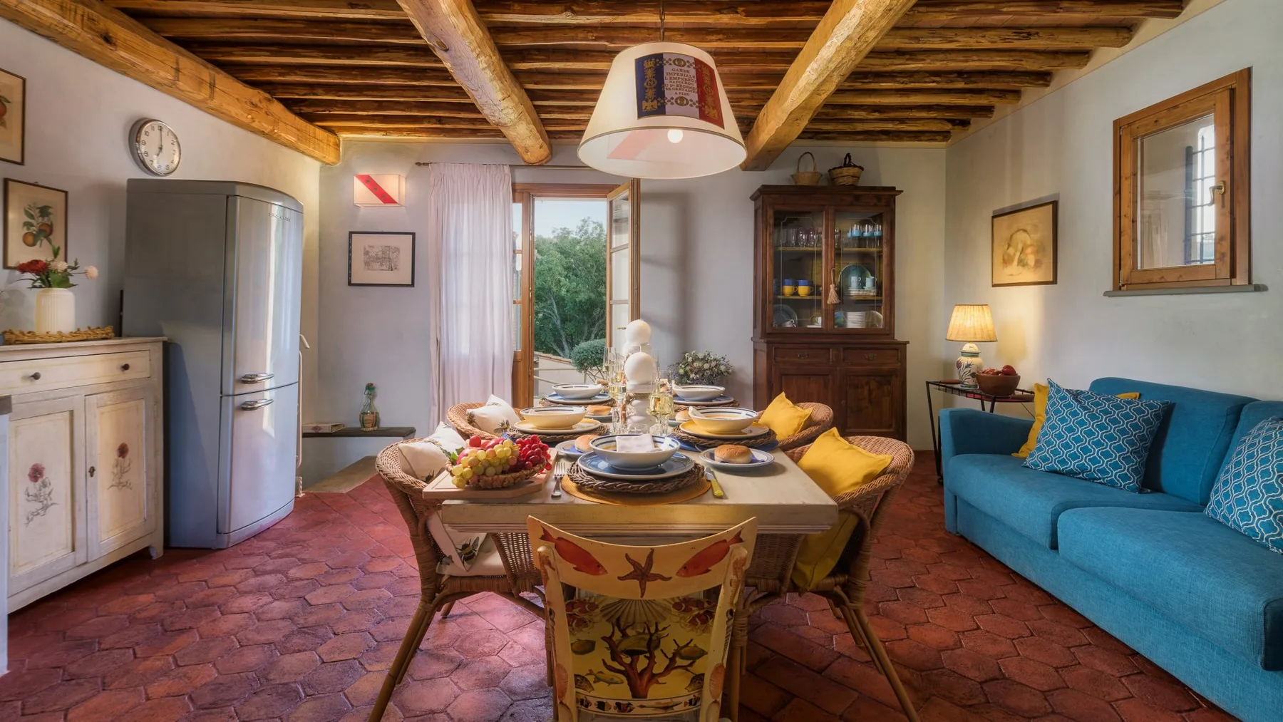Comedor y sala de estar con una mesa de madera, asientos azules y vigas expuestas.