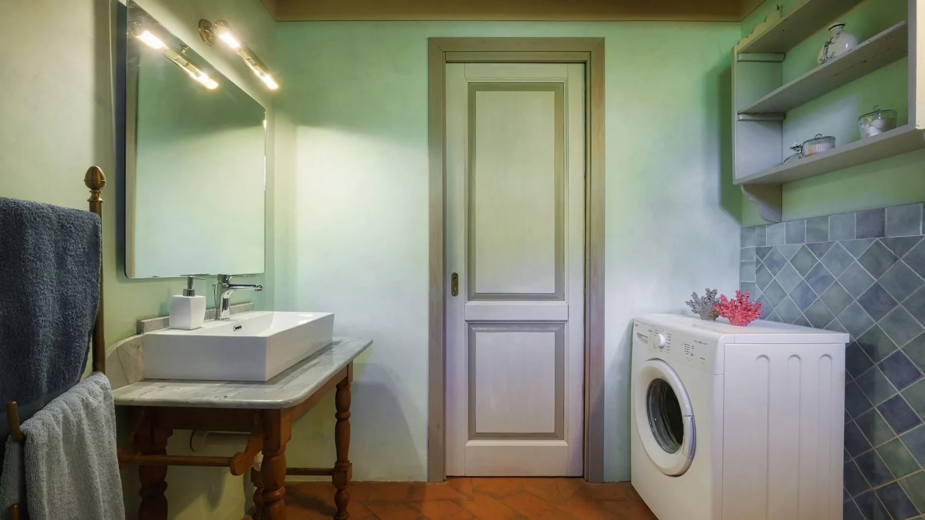 Un baño con lavabo, lavadora y estantes en la pared.