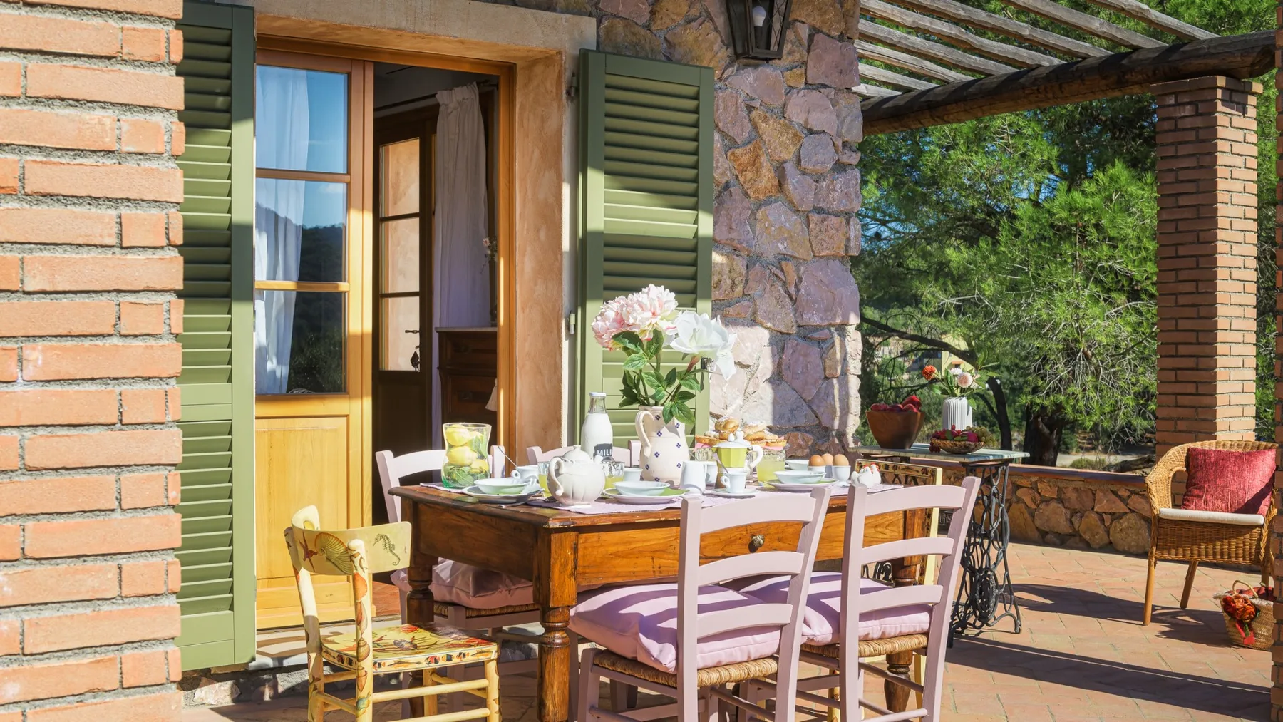 Un comedor exterior soleado con una mesa puesta junto a una puerta abierta.
