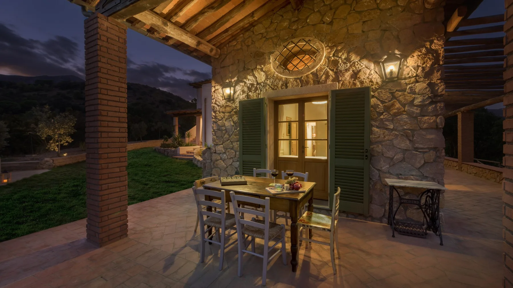 Una zona de comedor al aire libre junto a un edificio de piedra, con una mesa de madera y sillas.